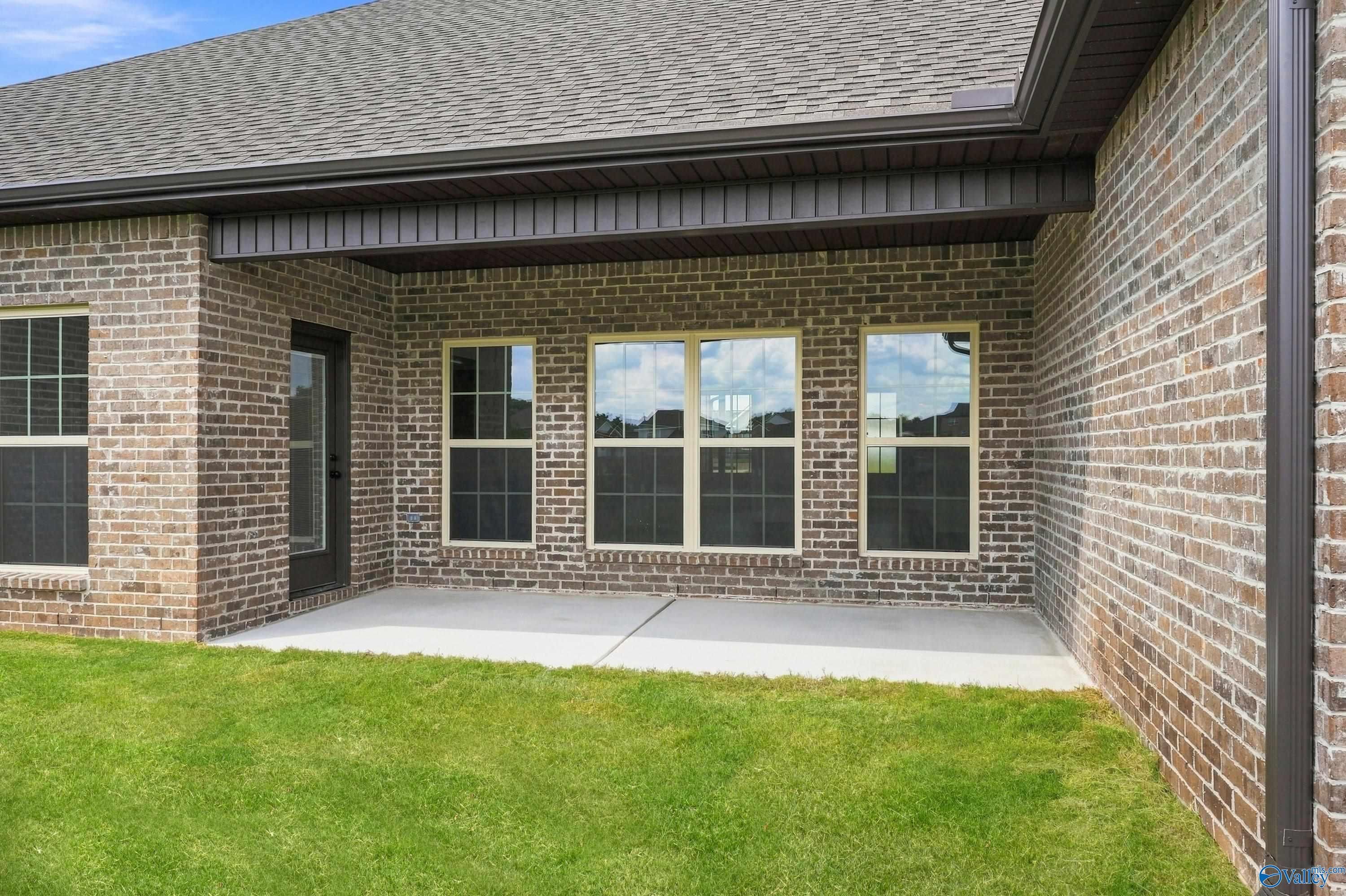 Covered brick patio with large windows overlooking green backyard at Davidson Homes The Valencia in Riverton Preserve, Huntsville