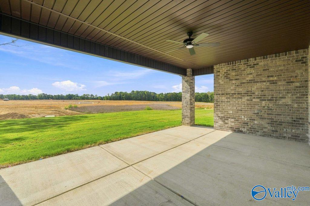 Covered back patio with ceiling fan overlooking a spacious backyard in Cain Park, Hartselle, Alabama.