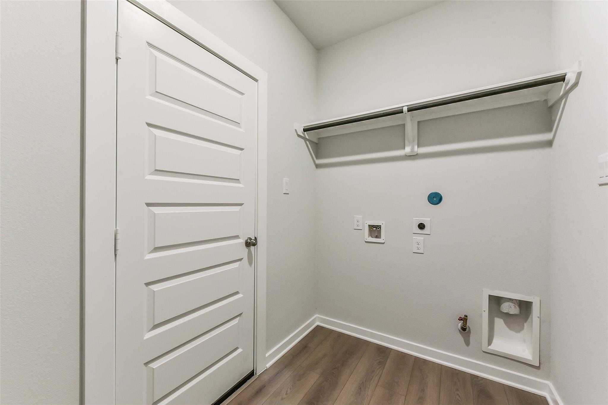 Modern laundry room with built-in shelves, washer/dryer hookups and utility sink in Davidson Homes The Frio F, Dayton Texas