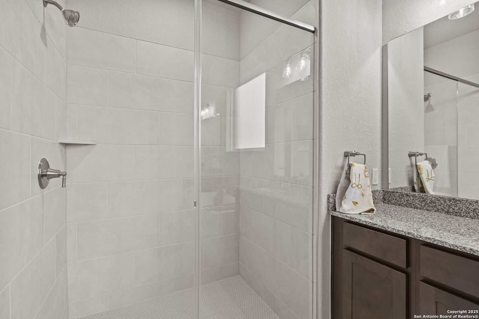 Modern master bathroom featuring walk-in glass shower, granite vanity, and white subway tile in Davidson Homes The Jennings G, Castroville, Texas