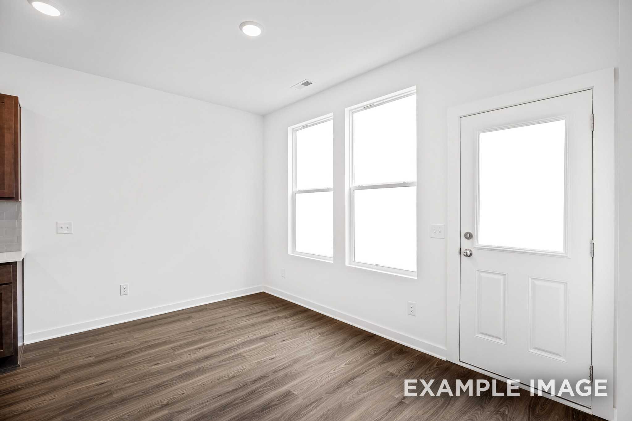 Bright dining nook in The Grayson C with large windows, hardwood floors, and white cabinetry, Davidson Homes design