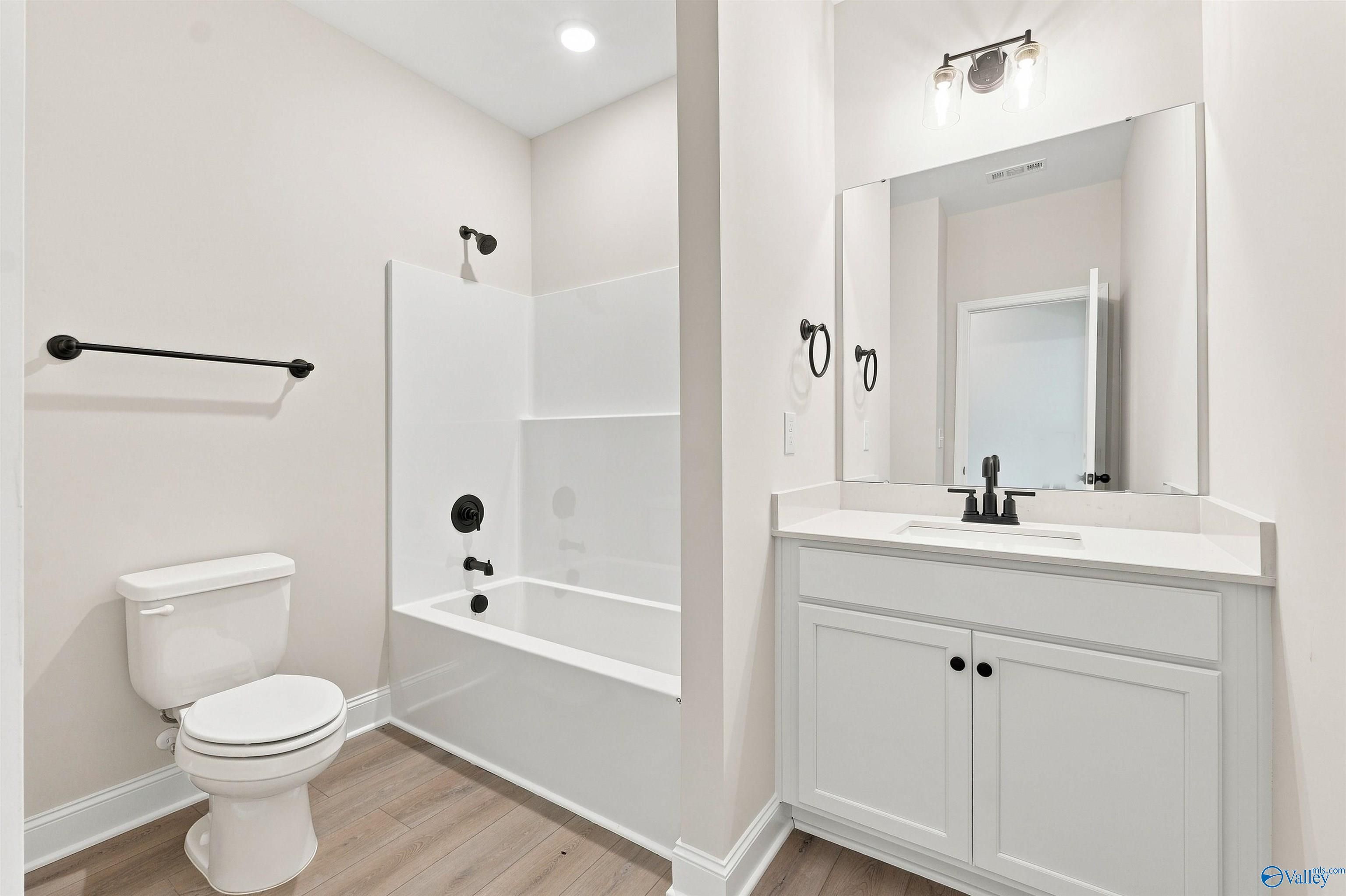 Bright bathroom with white vanity, black fixtures, and tub-shower combo in Davidson Homes The Everett B, Wood Trail, Toney, Alabama