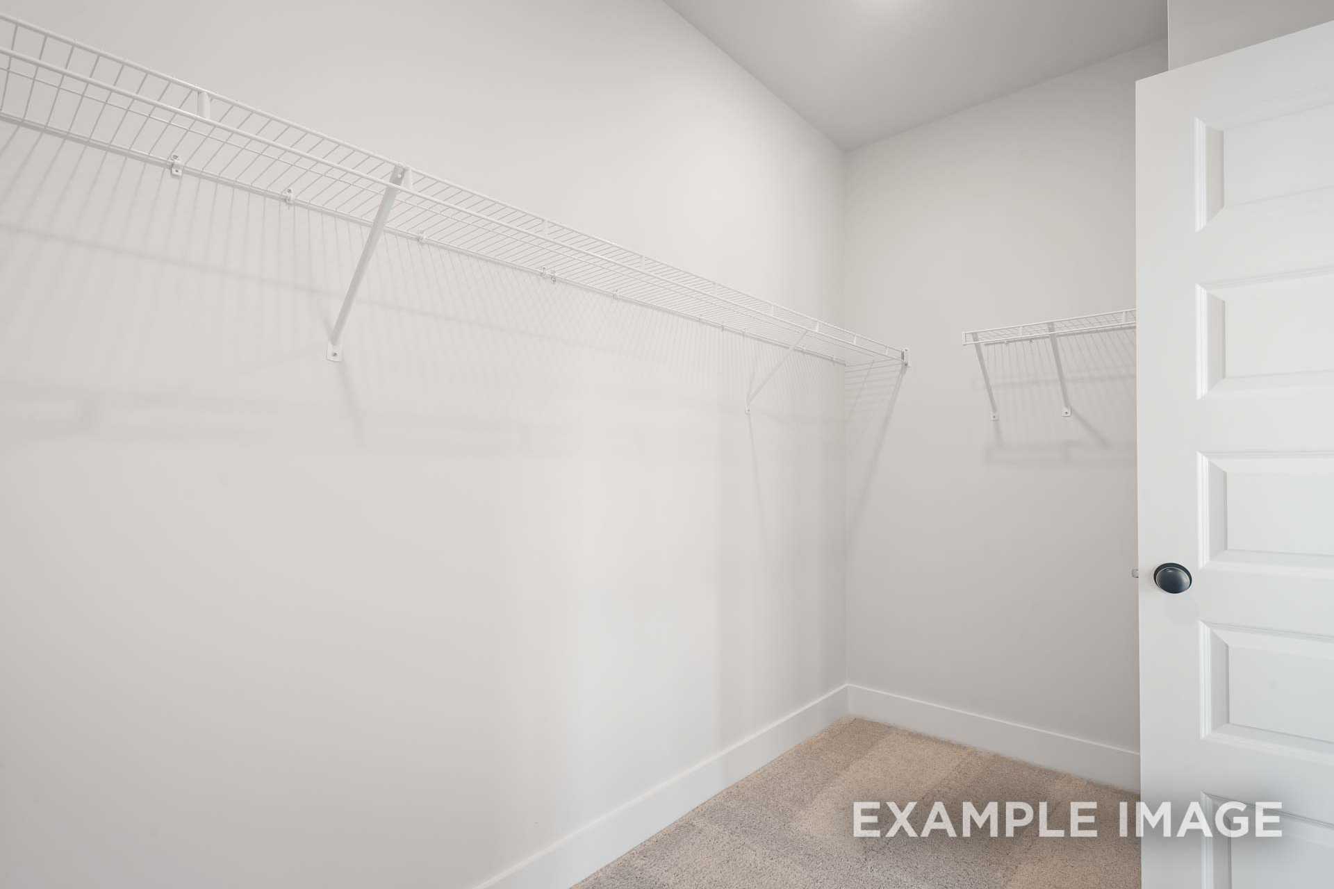 Spacious walk-in closet in The Ridgeport B master suite with white wire shelving and hanging rods