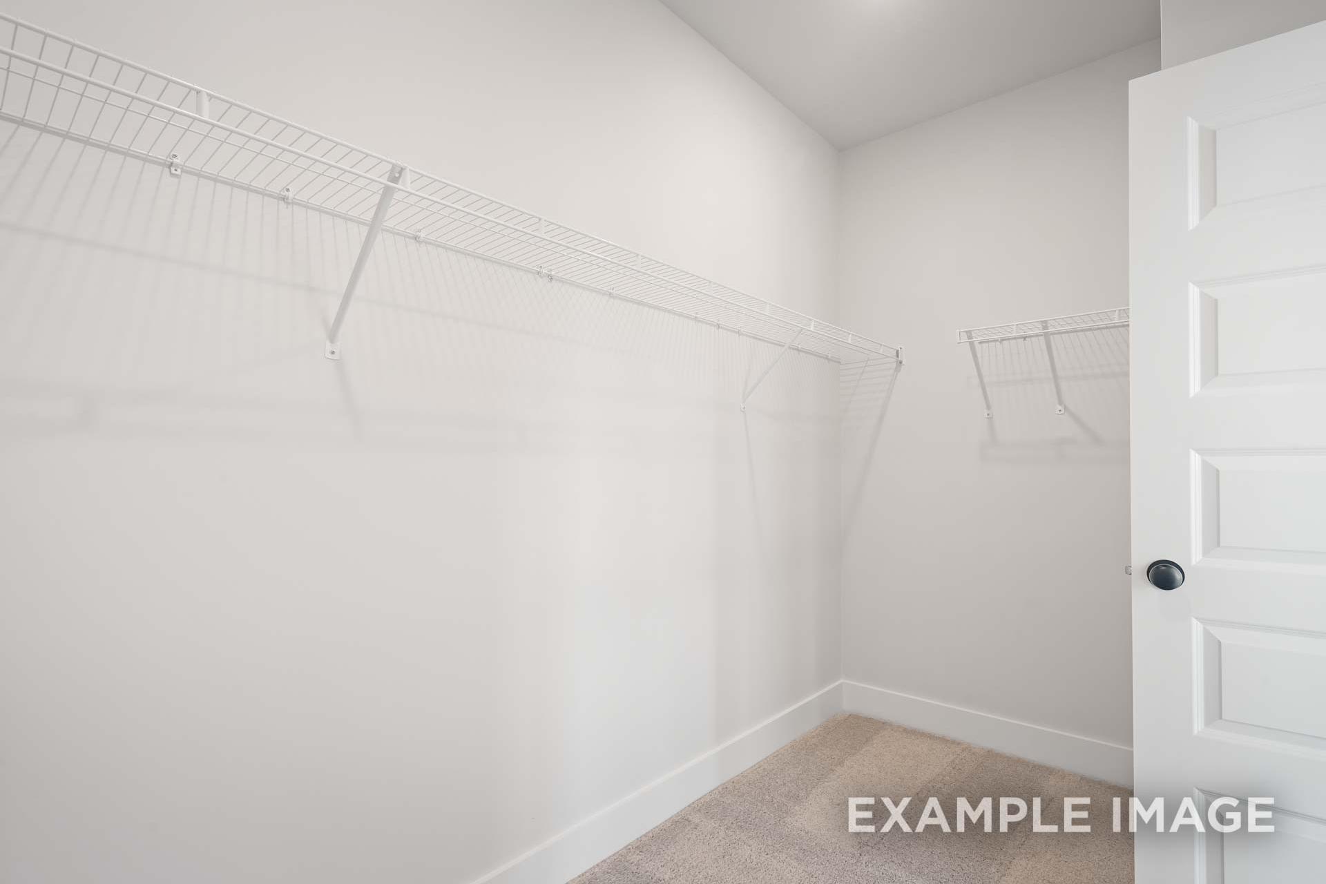 Spacious walk-in closet in The Ridgeport B master suite with white wire shelving and hanging rods