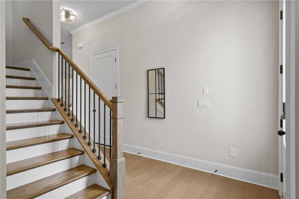 Elegant oak staircase with wrought iron balusters in foyer of The Seaside B 2-story home, Woodstock, Georgia