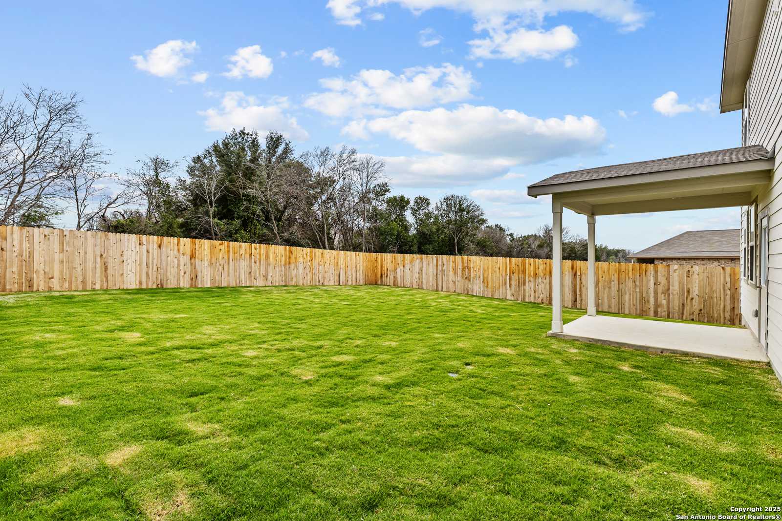 Expansive green backyard with covered patio, wooden privacy fence, and mature trees in Davidson Homes The Douglas F, Royal Crest, San Antonio, Texas
