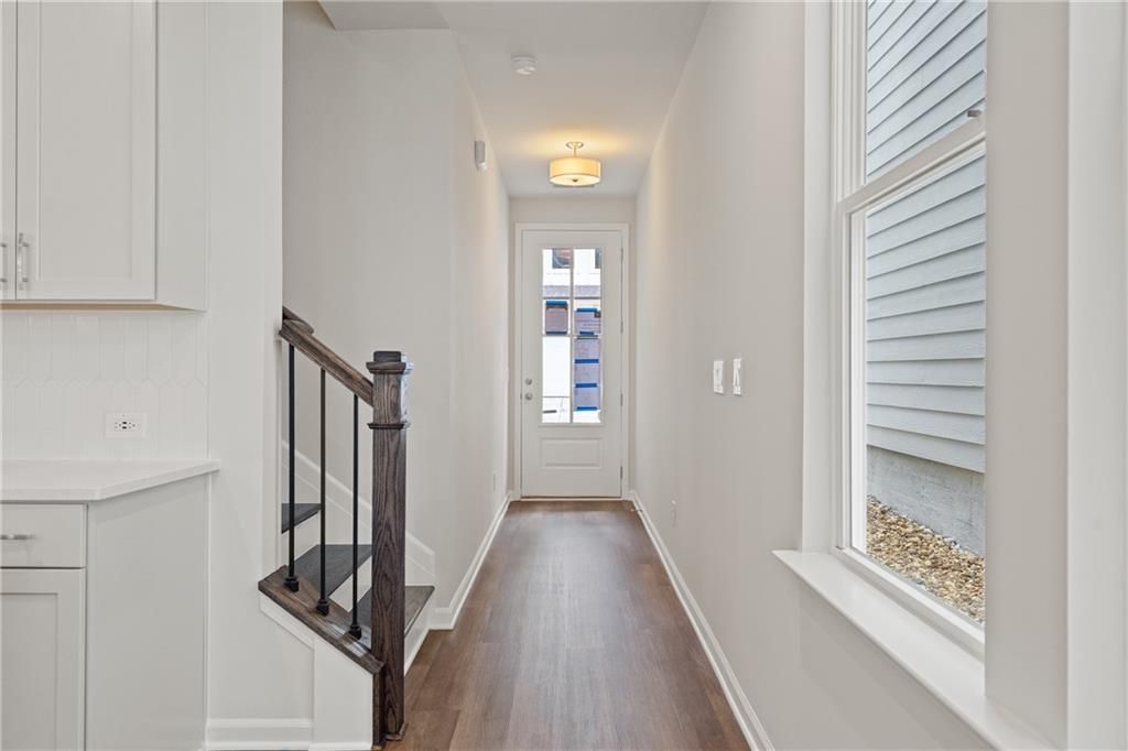 Bright entry hallway with oak staircase and white cabinetry in Davidson Homes The Cary B, Kennesaw, Georgia