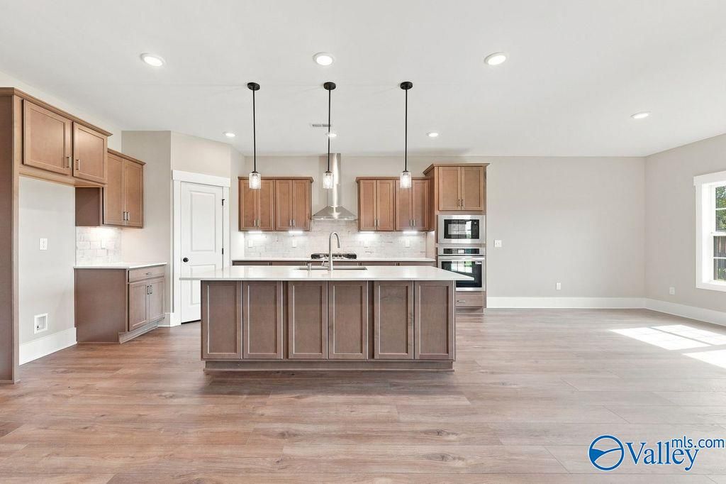 Open-concept kitchen with large island and wood cabinets in The Rockford floor plan at Cain Park, Hartselle, Alabama.