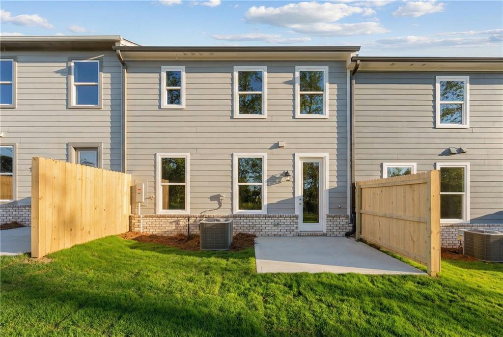 Fenced backyard with green lawn and concrete patio at rear of two-story gray Davidson Homes The Marion A in Winder, Georgia