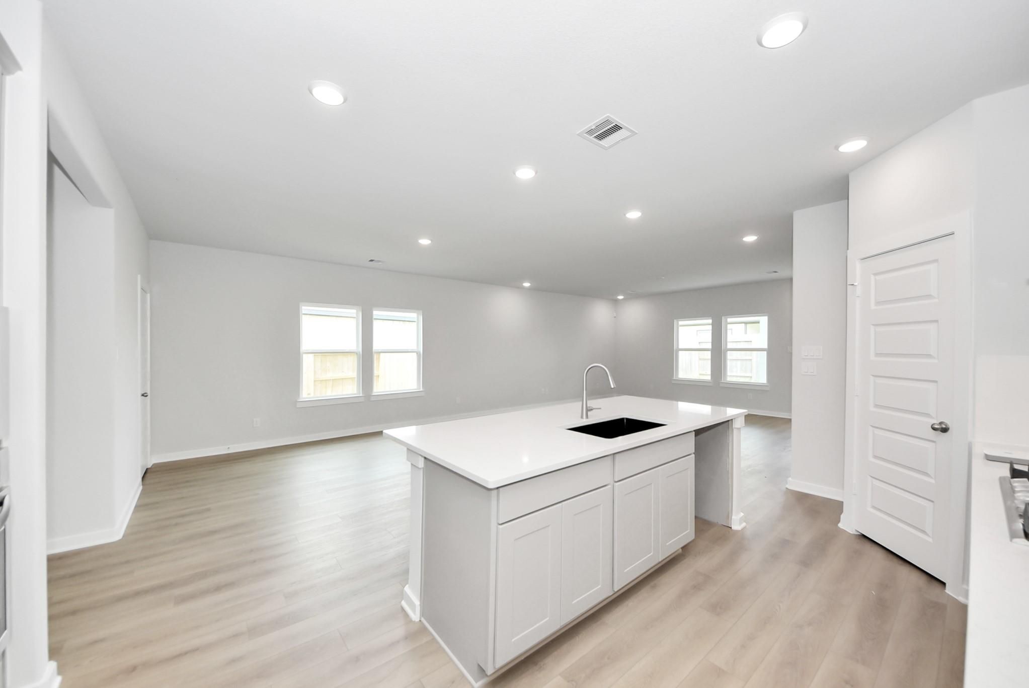 Open-concept kitchen and living area with white quartz island in The Verano B floor plan, Sunterra, Katy, Texas.