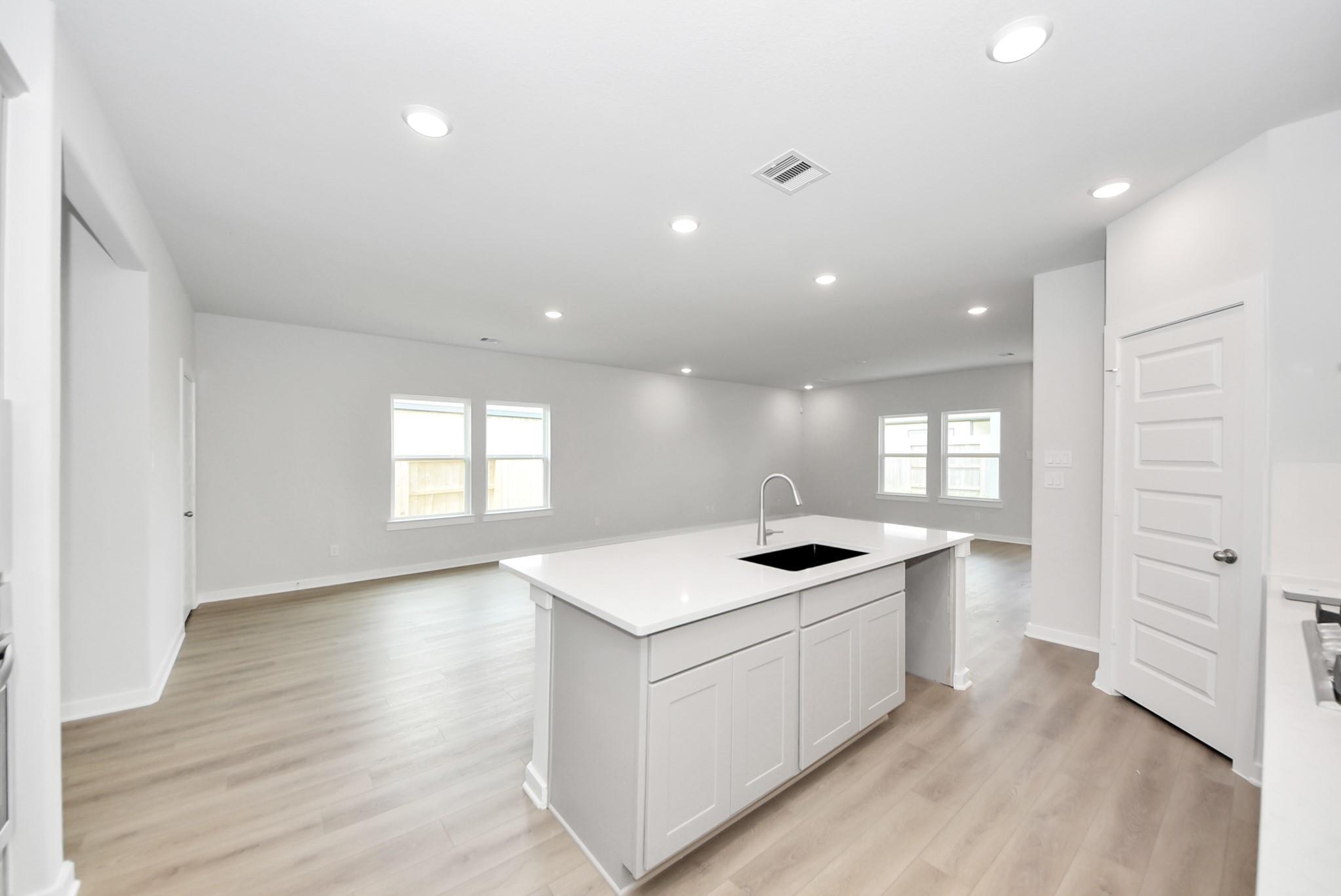 Open-concept kitchen and living area with white quartz island in The Verano B floor plan, Sunterra, Katy, Texas.