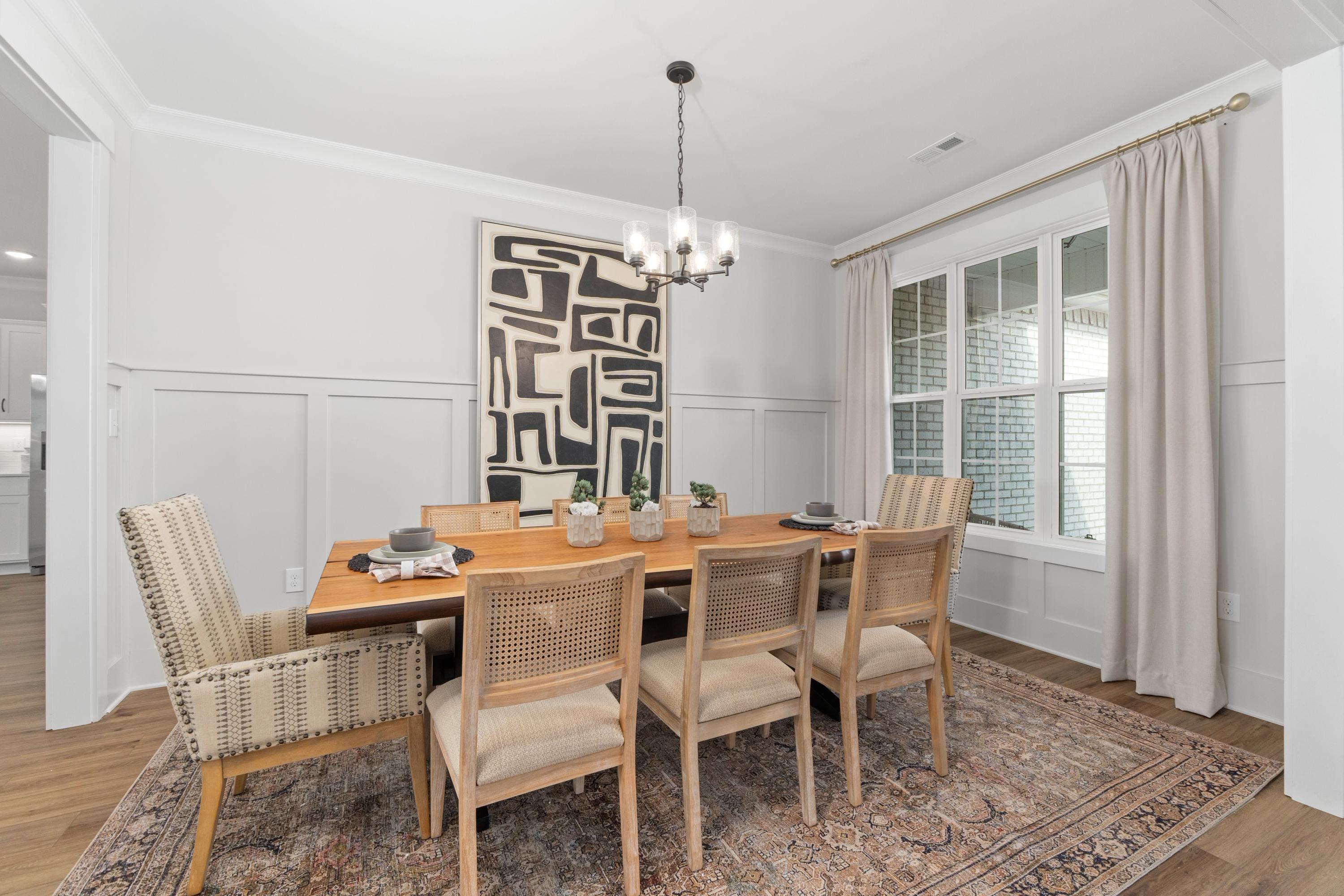 Elegant dining room in Briercreek Meridianville AL by Davidson Homes featuring wooden table, rattan chairs, abstract art, and chandelier