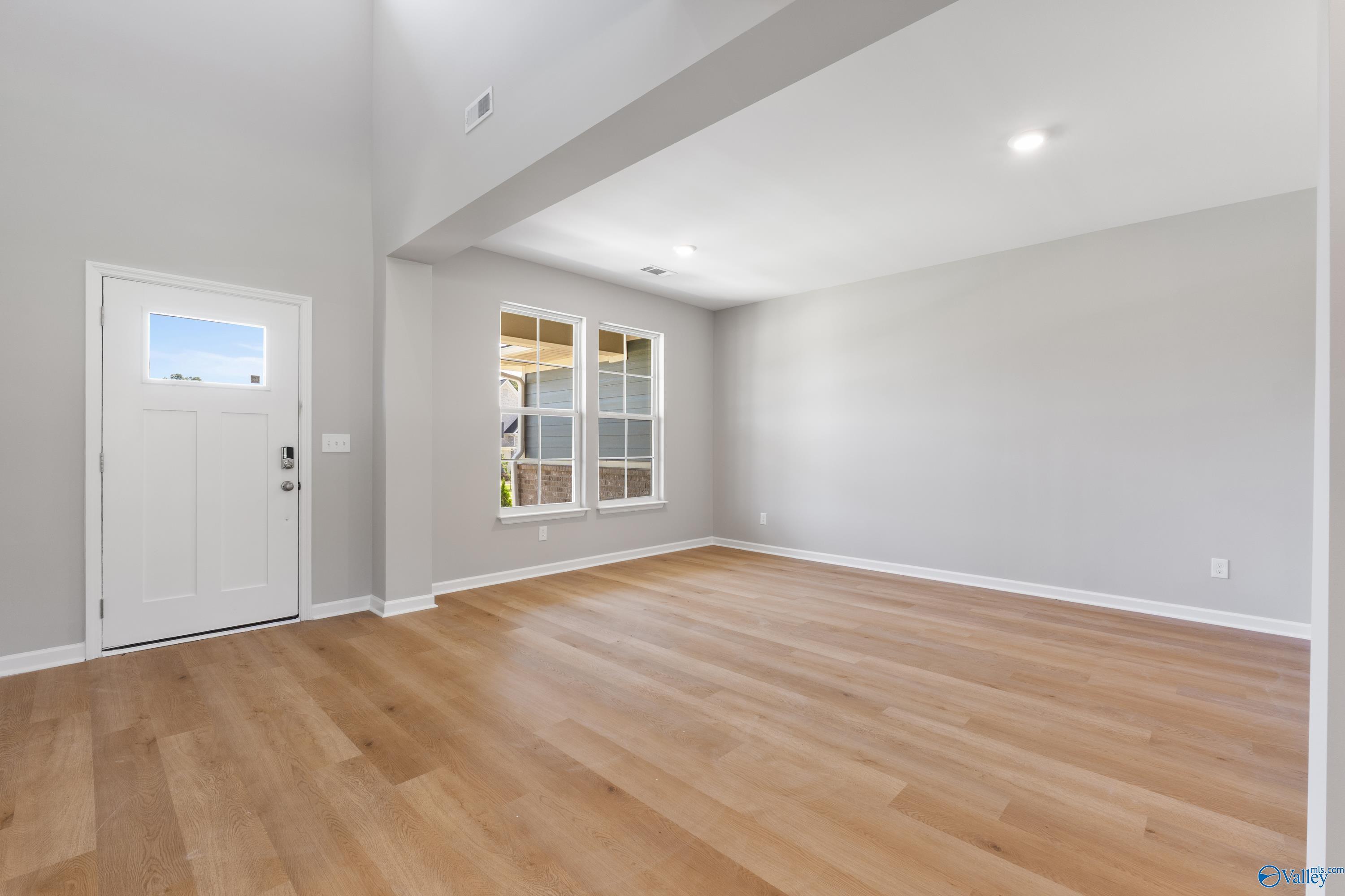 Spacious entry foyer with hardwood floors, high ceilings, and large grid windows in Davidson Homes The Charm, Huntsville, AL