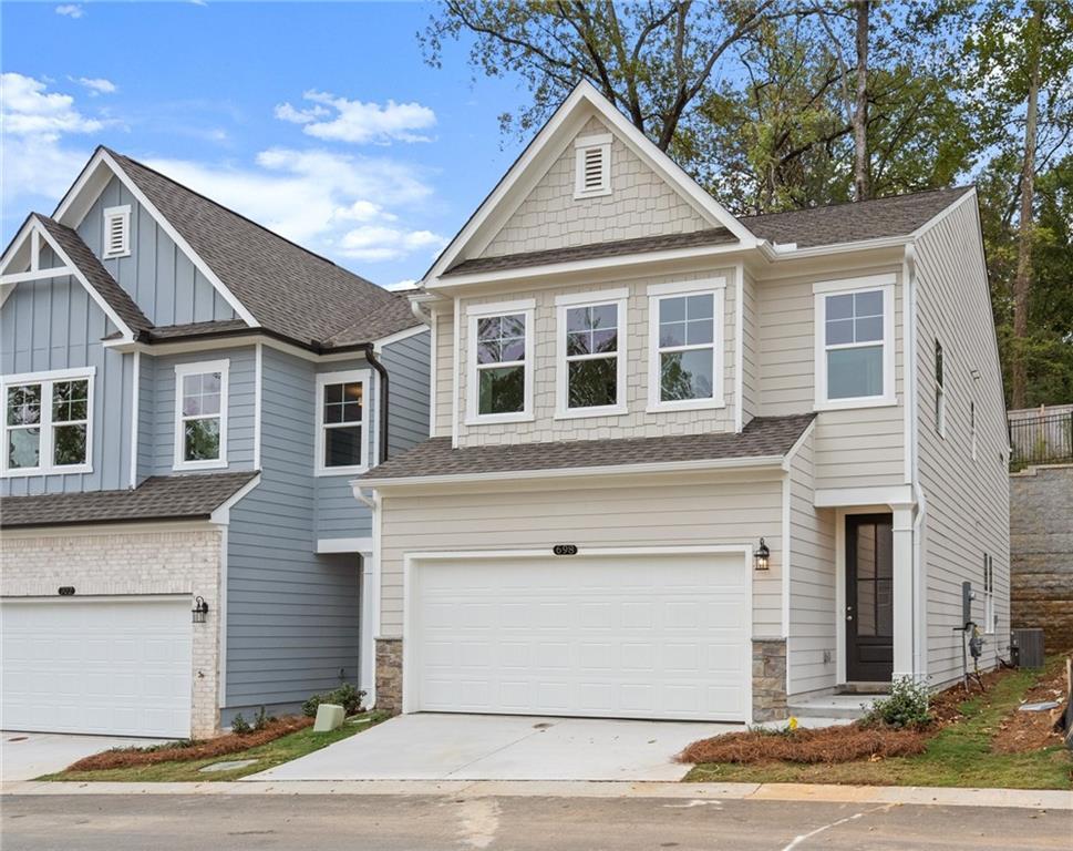 Modern two-story beige townhome with 2-car garage, gabled roof, and stone accents in The Village at Shallowford, Kennesaw, Georgia