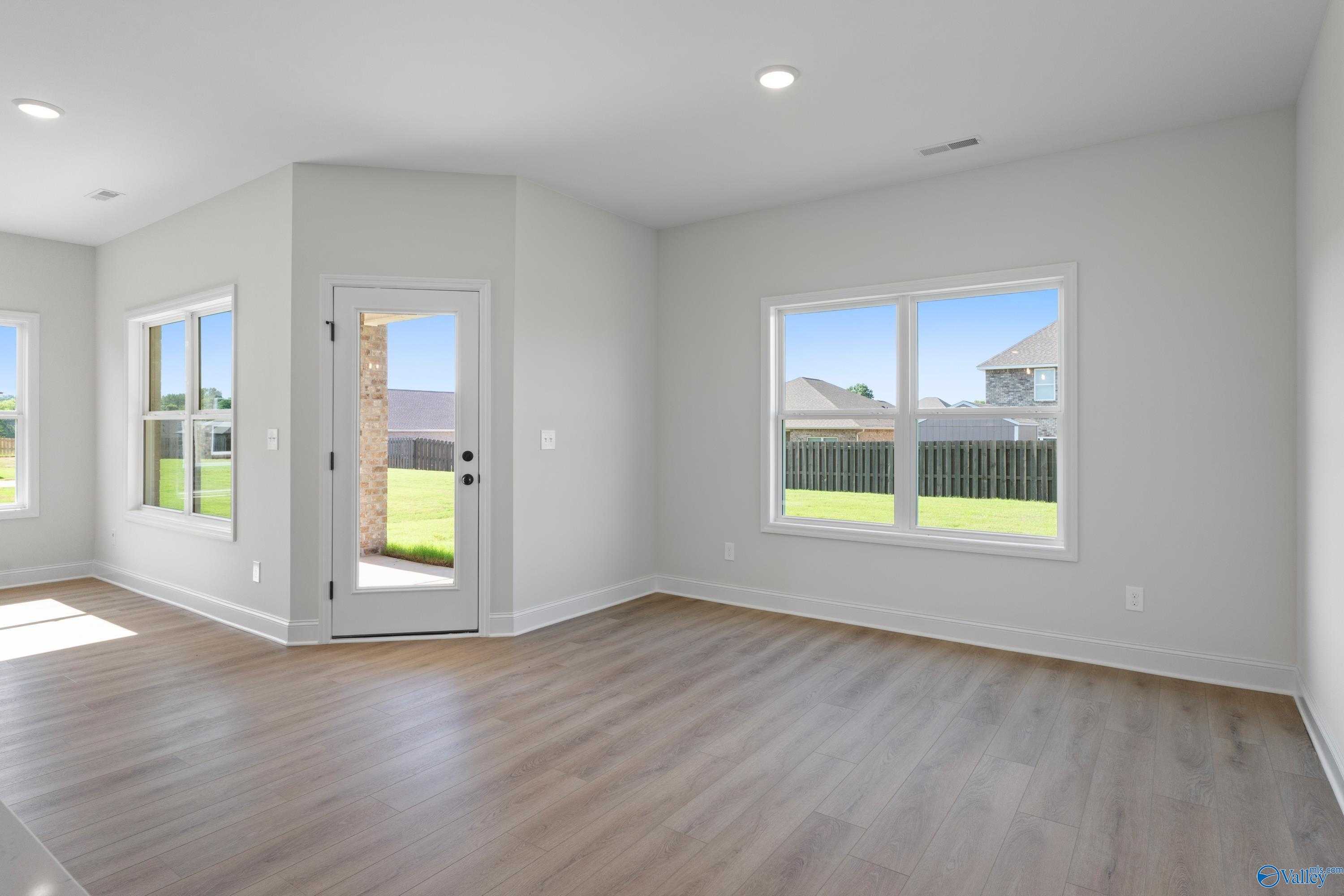Bright living room with large windows, glass door to fenced backyard in Davidson Homes The Franklin C, Hazel Green AL