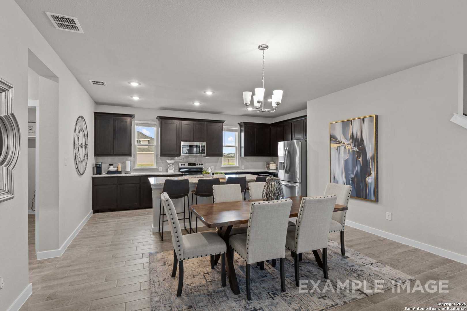 Modern open-concept kitchen and dining with dark cabinets, stainless appliances, chandelier in The Collin B, Seguin, Texas