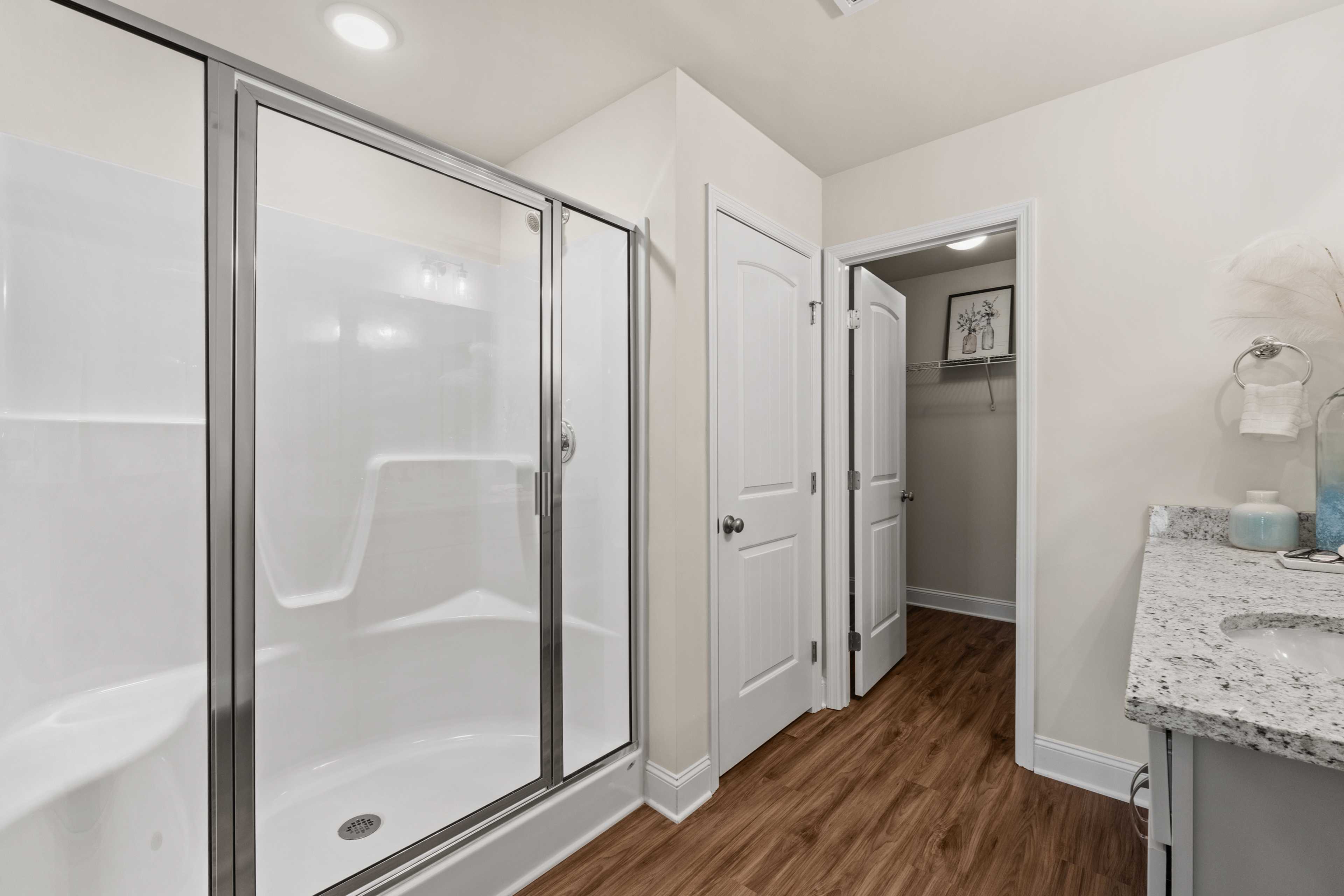 Contemporary bathroom at Ramsay Cove in Owens Cross Roads AL with frameless glass shower, quartz vanity, and hardwood floors
