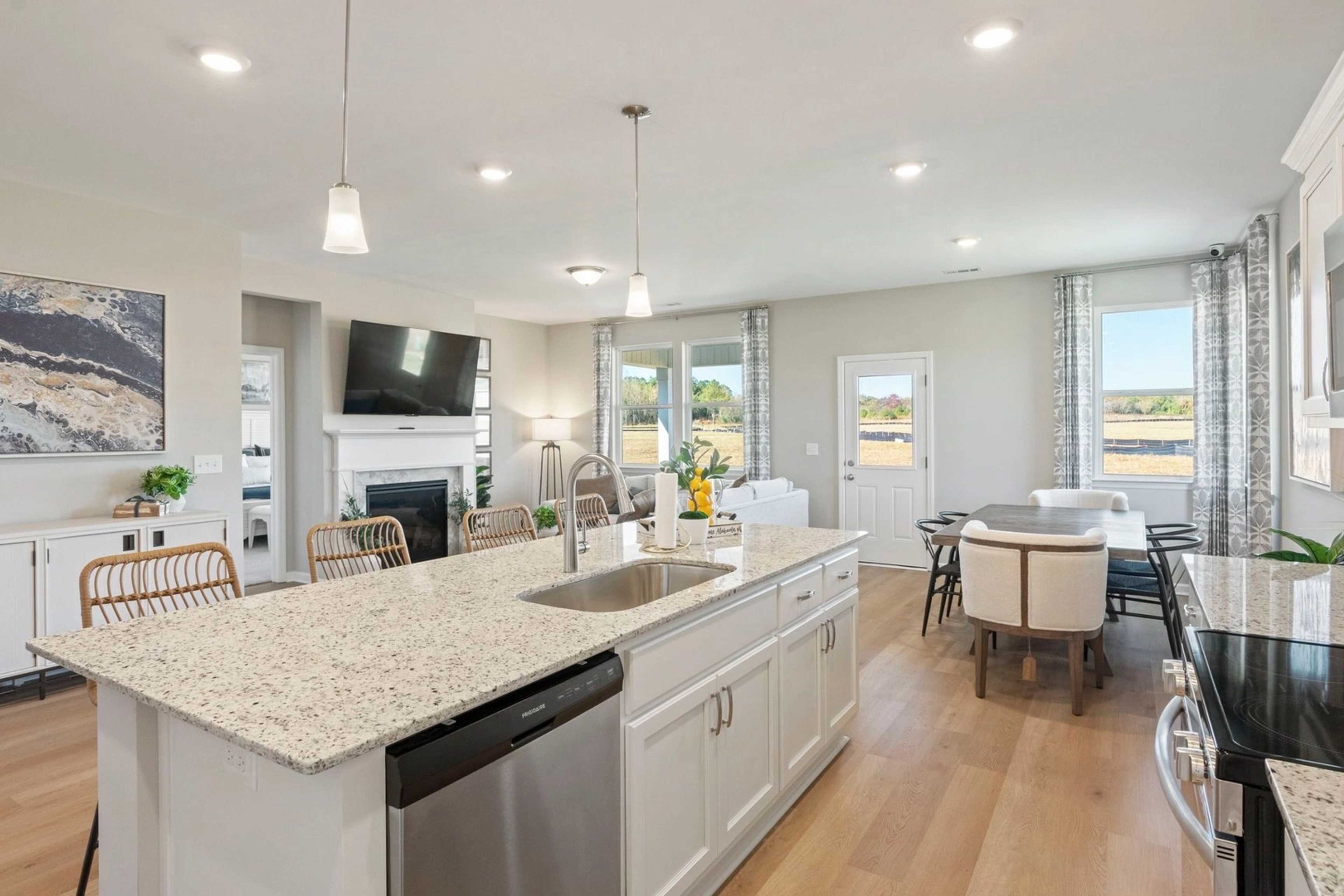 Spacious open-concept kitchen and dining area in Bailey Park, Fayetteville TN with white cabinets, granite island, hardwood floors, and large windows