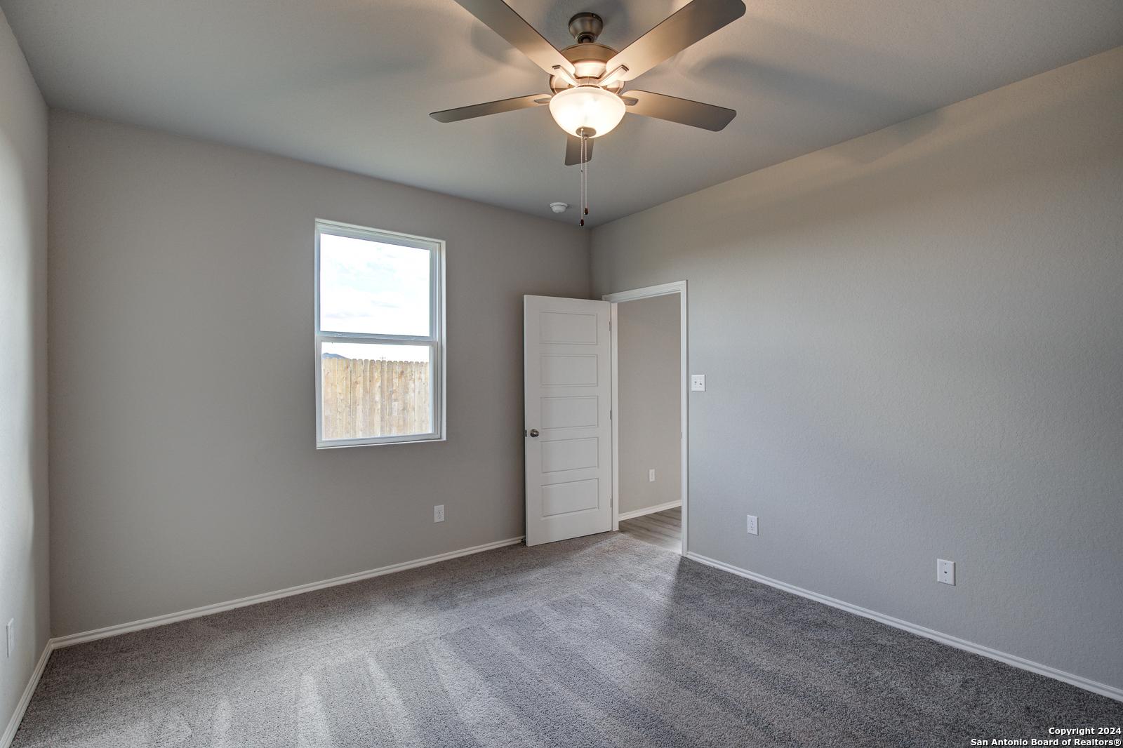 Bright secondary bedroom with gray walls, ceiling fan, carpet floor, and window in Davidson Homes The Blanco C, Applewhite Meadows, San Antonio