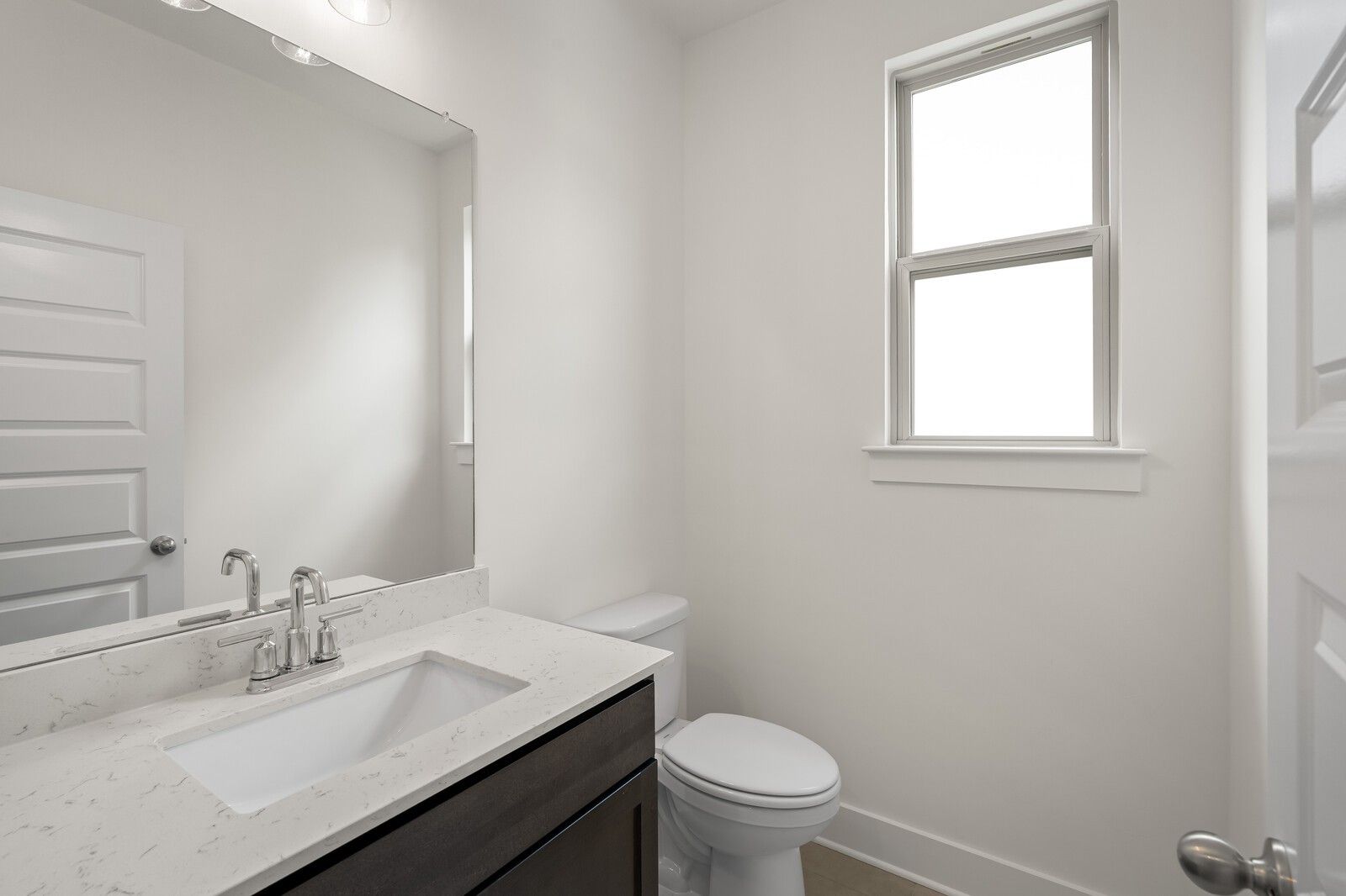 Modern half bathroom with marble-style vanity and large mirror in The Ridgeport C floor plan, Woods Crossing, Gallatin, TN.