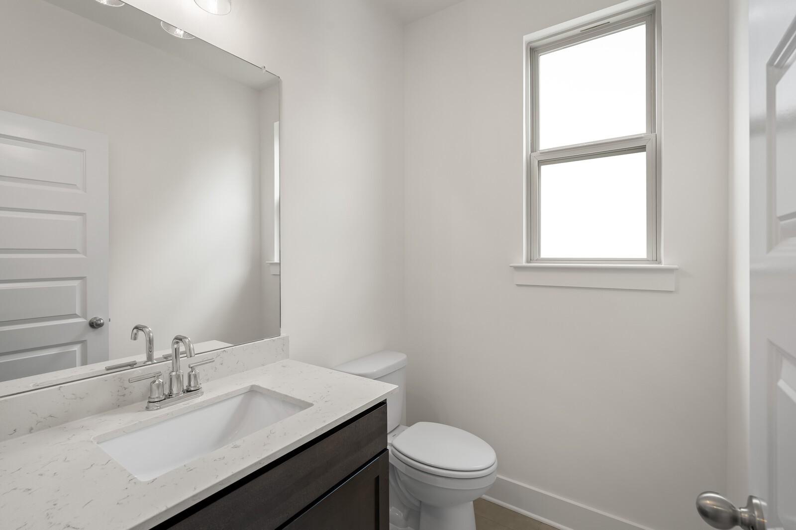 Modern half bathroom with marble-style vanity and large mirror in The Ridgeport C floor plan, Woods Crossing, Gallatin, TN.