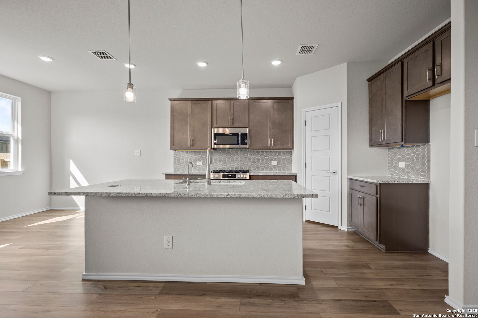 Modern open-concept kitchen with quartz island, stainless appliances, shaker cabinets in Davidson Homes The Asheville J, San Antonio