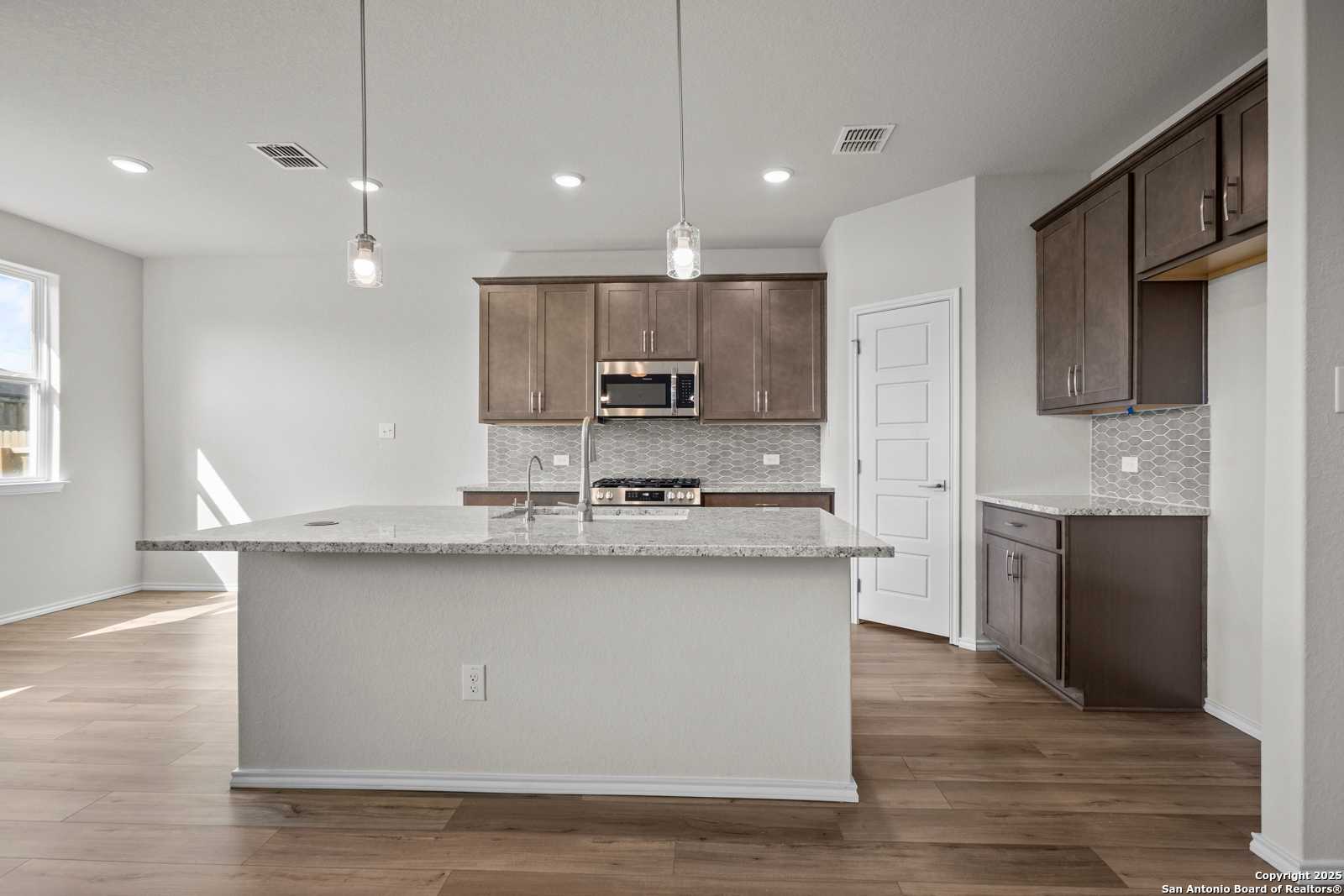 Modern open-concept kitchen with quartz island, stainless appliances, shaker cabinets in Davidson Homes The Asheville J, San Antonio