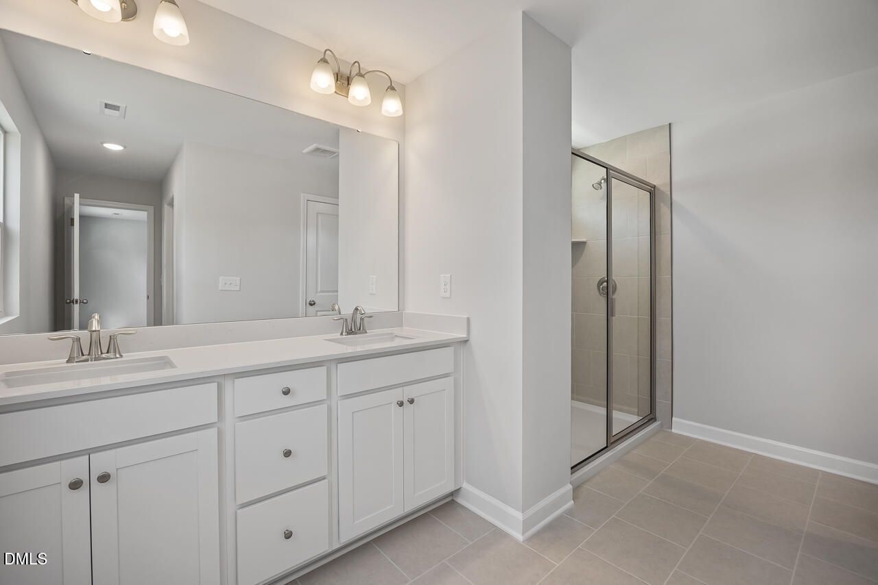 Modern bathroom with double vanity and glass-enclosed shower in The Adalynn B floor plan, Gregory Village, Lillington, NC.