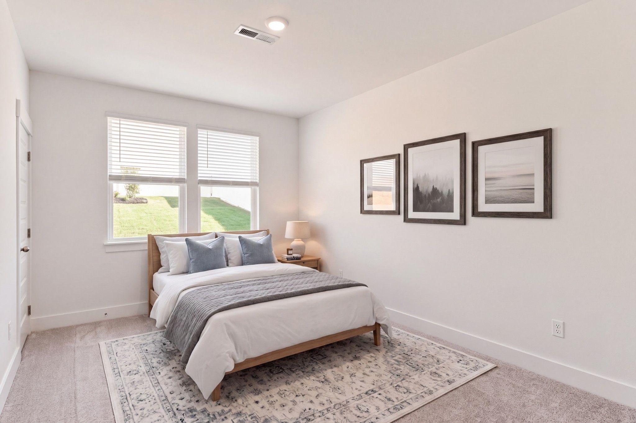 Bright bedroom with wood bed, blue accents, and gallery wall in Davidson Homes The Willow C, Gallatin, Tennessee