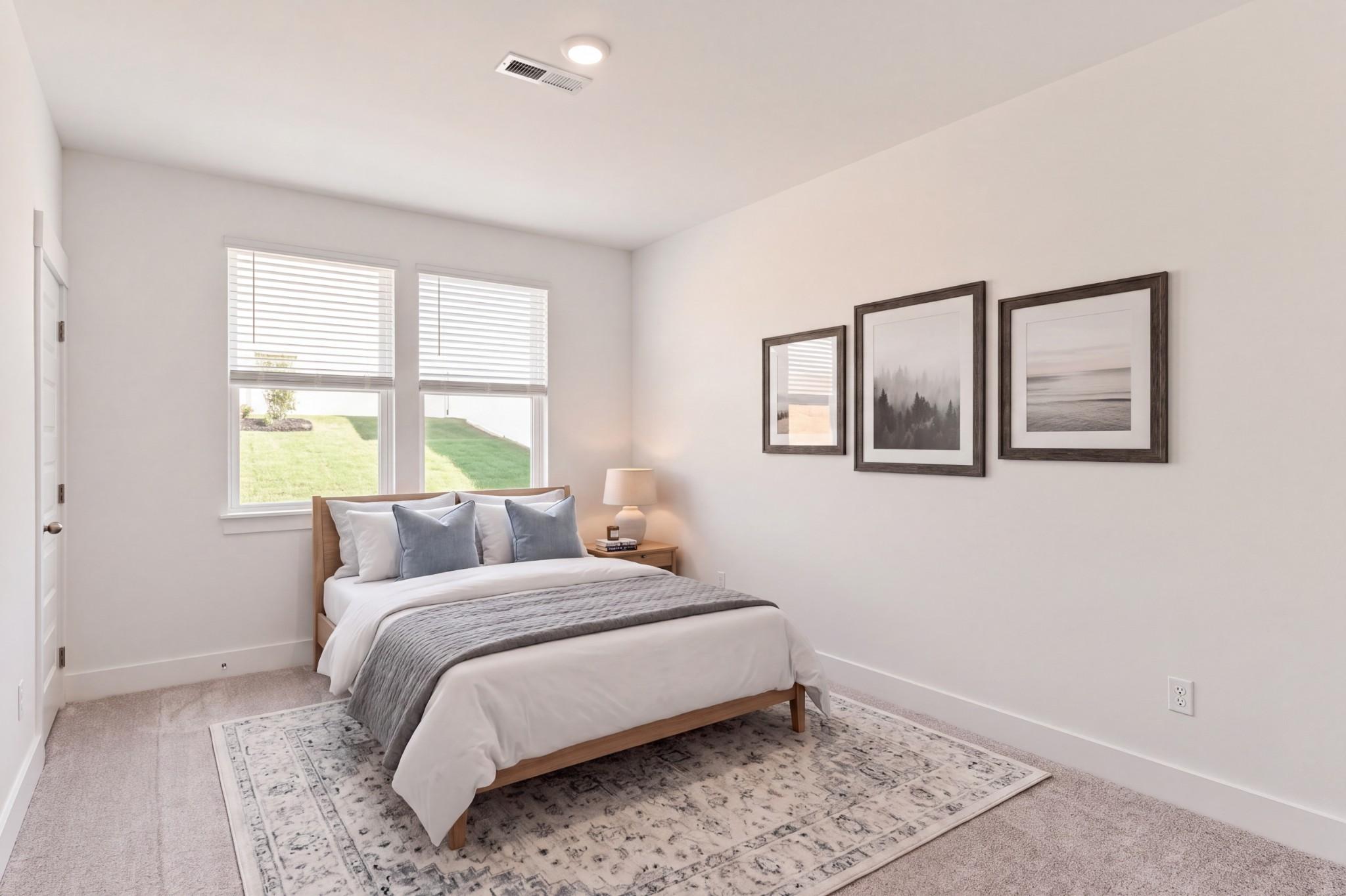 Bright bedroom with wood bed, blue accents, and gallery wall in Davidson Homes The Willow C, Gallatin, Tennessee