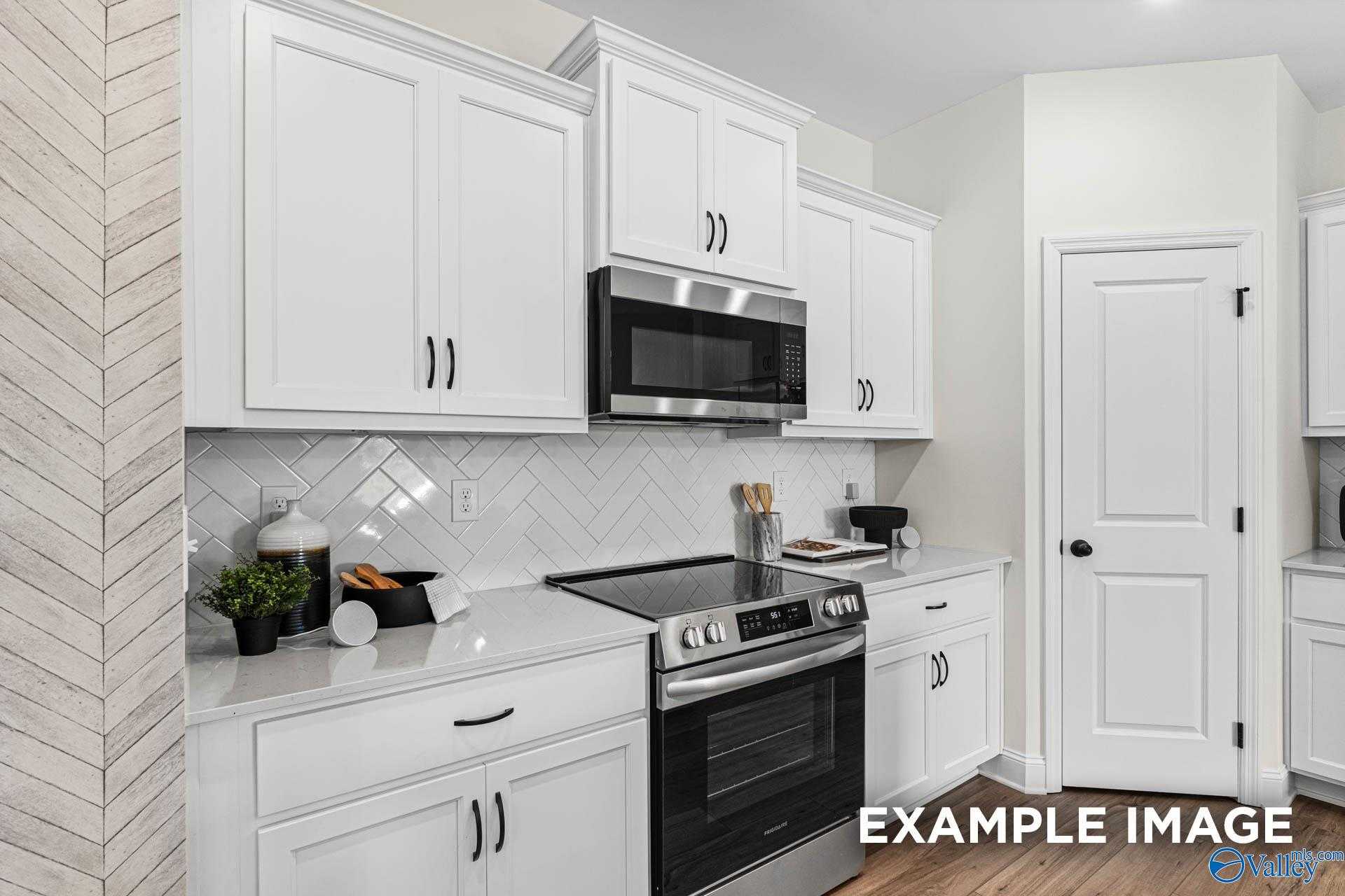 Bright modern kitchen with white shaker cabinets, stainless steel appliances, subway tile backsplash, and shiplap wall in Davidson Homes The Franklin, Huntsville AL