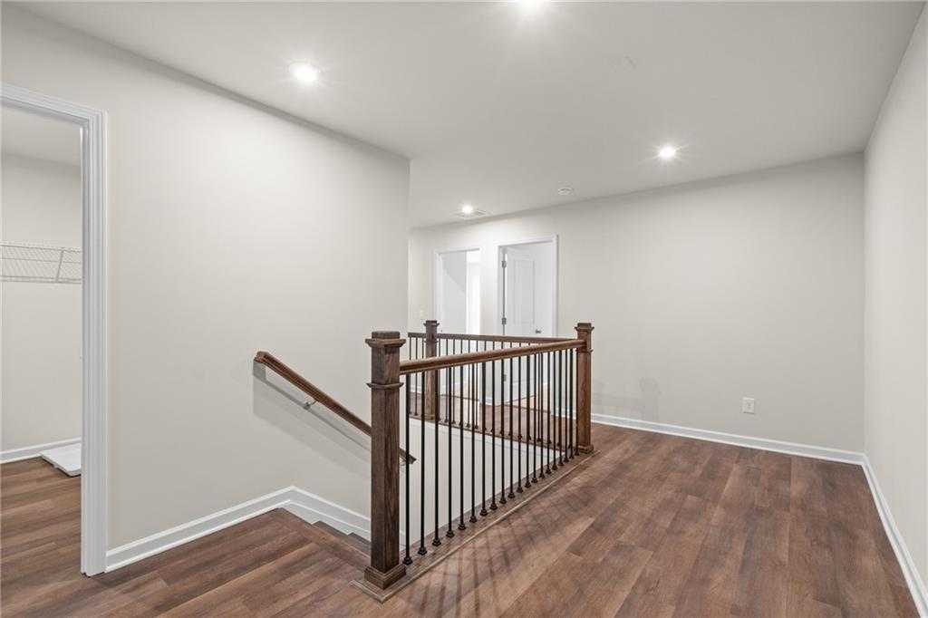 Spacious upstairs hallway with hardwood floors, wooden staircase, and wrought iron railing in Davidson Homes The Marion B, Kennesaw, GA