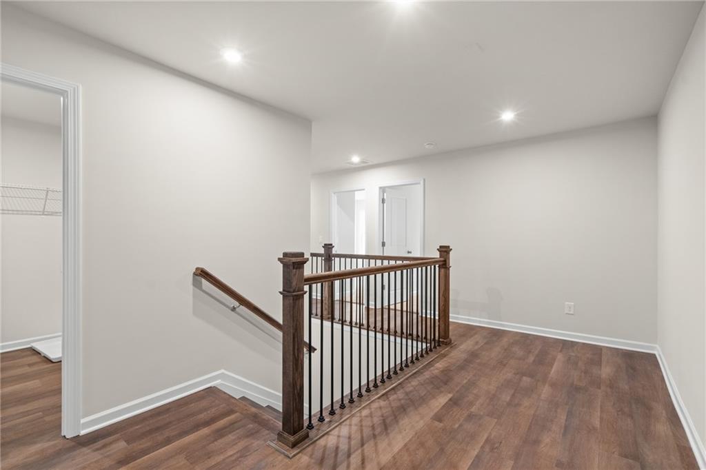 Spacious upstairs hallway with hardwood floors, wooden staircase, and wrought iron railing in Davidson Homes The Marion B, Kennesaw, GA