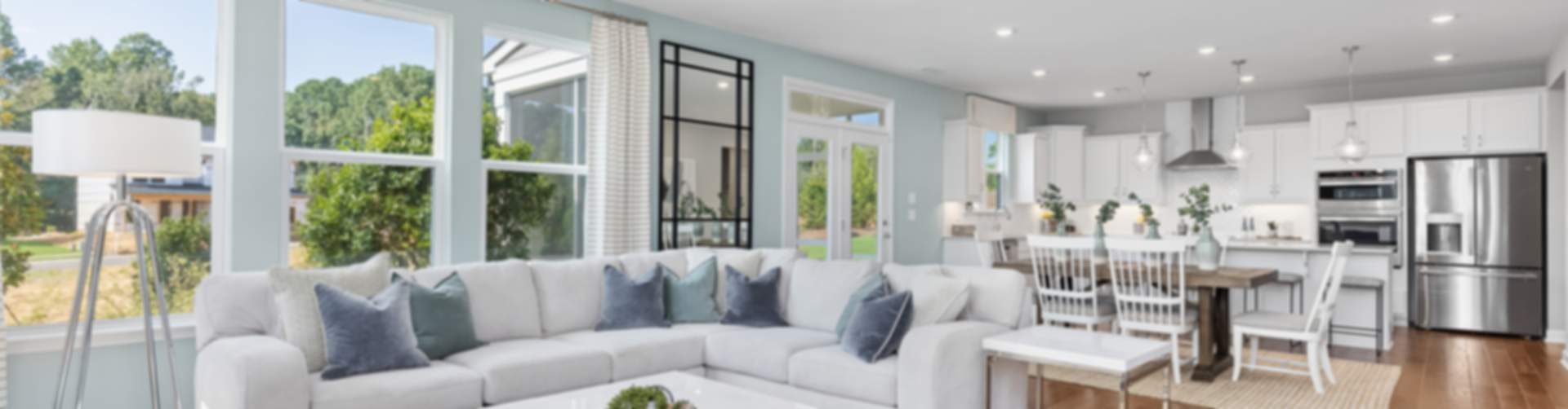 Spacious open-concept living room and kitchen in new Lillington home, white L-shaped sofa, wood floors, large windows