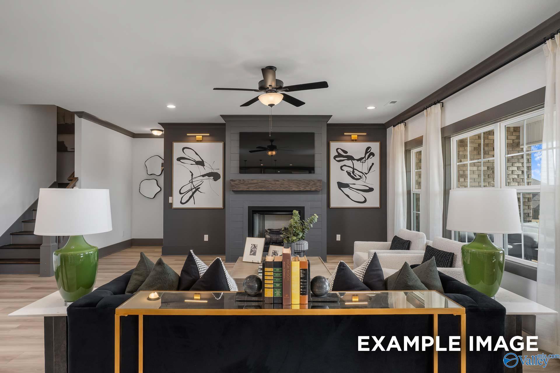 Modern living room with black sofa, gold coffee table, TV over fireplace, abstract art in Davidson Homes The Rockford B, Madison AL