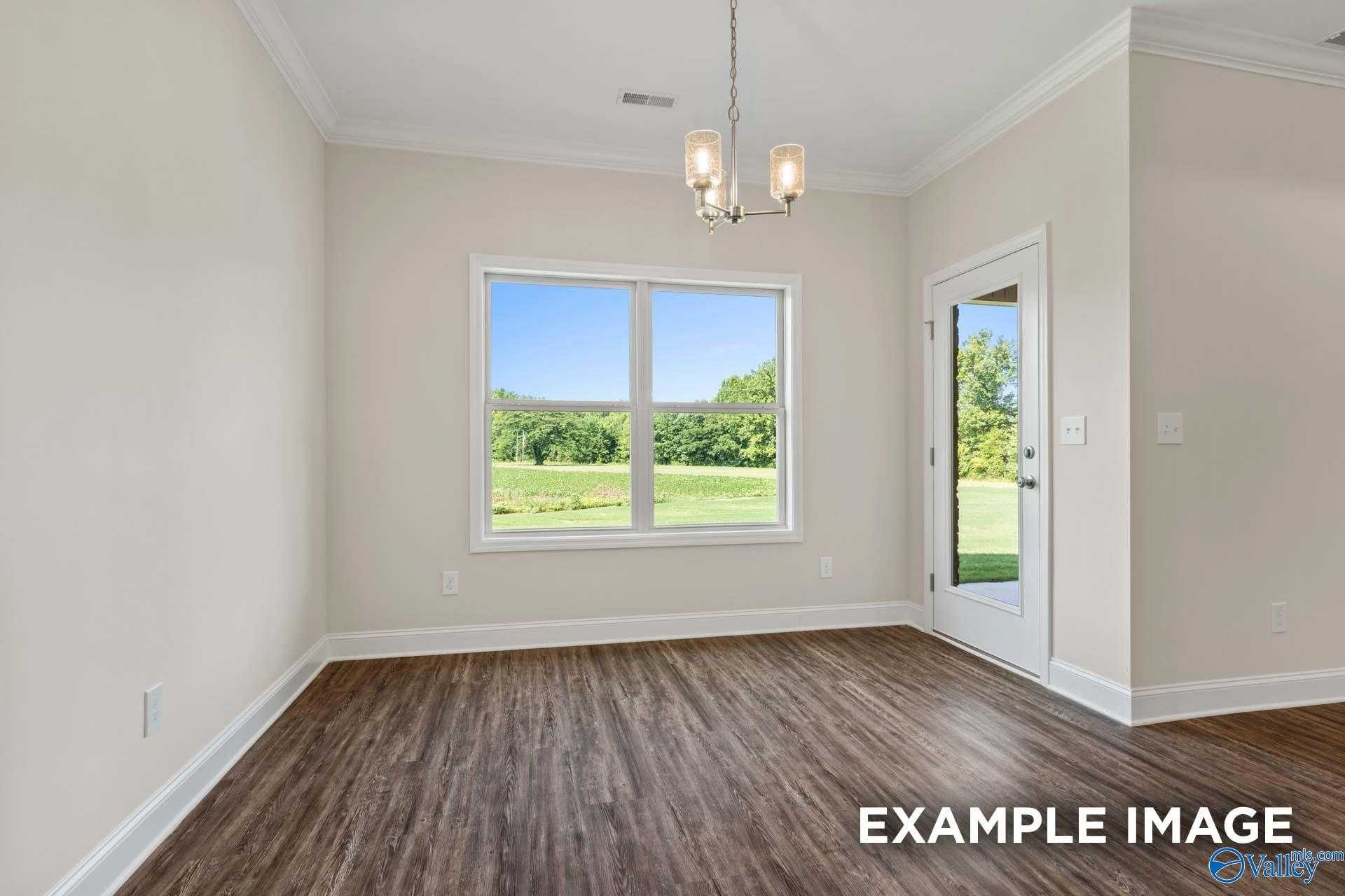 Bright sunroom with large windows and glass door overlooking lush green fields in The Asheville floor plan, Arab, Alabama