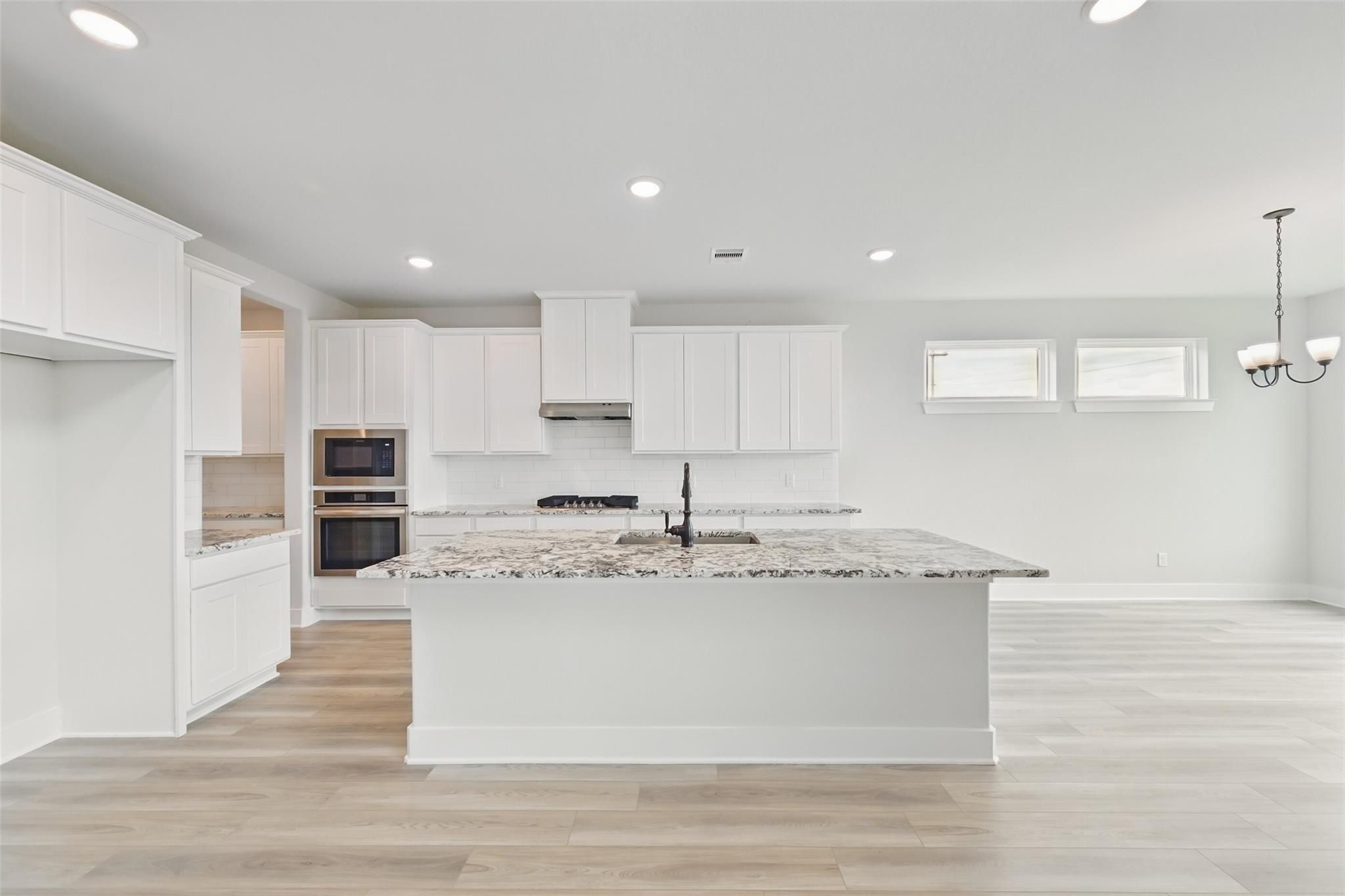 Modern white kitchen with granite island, stainless double oven, farmhouse sink in Davidson Homes The Victoria C, Lago Mar, Texas City