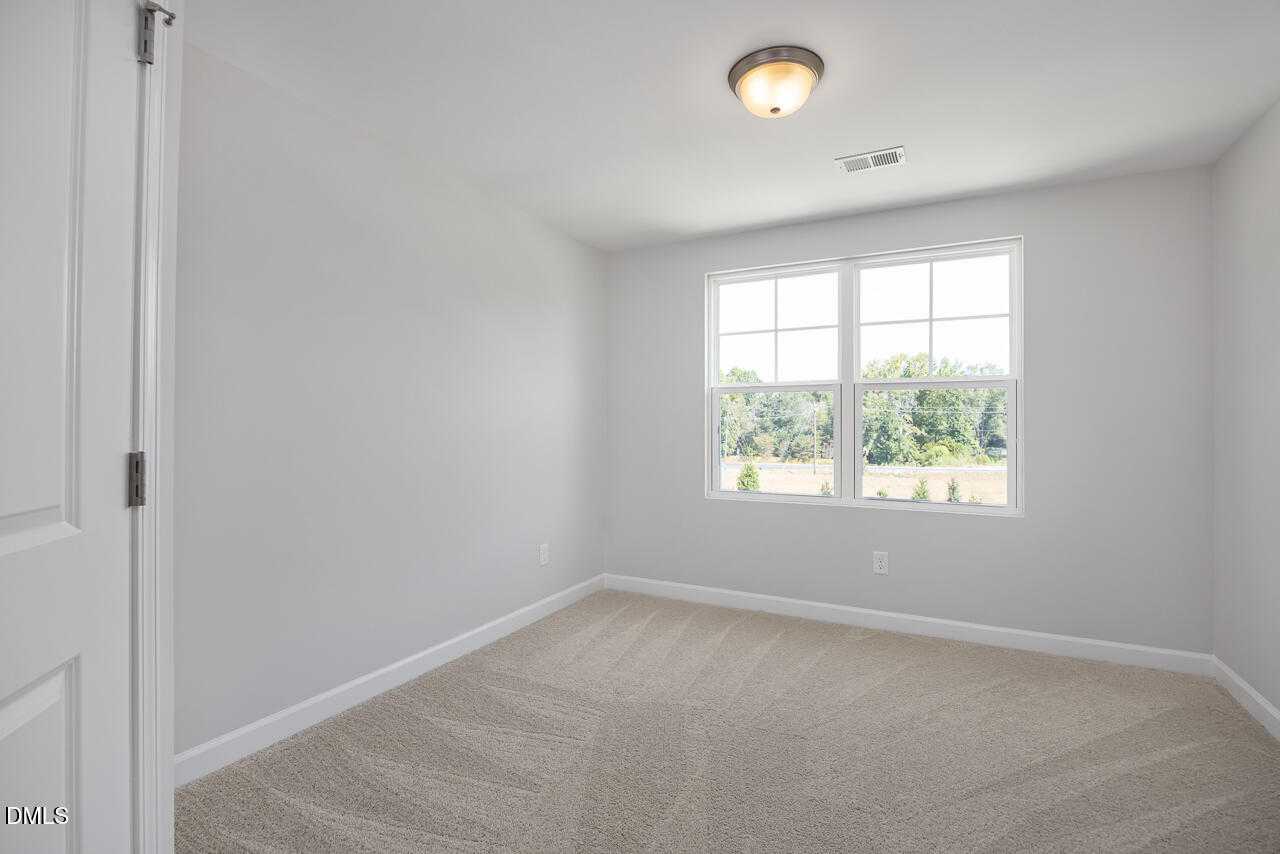 Bright secondary bedroom with large window and wooded view in The Graham Exterior home, Fuquay-Varina, NC