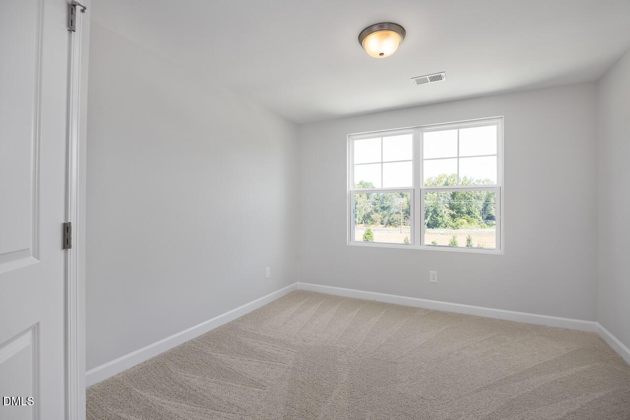 Bright secondary bedroom with neutral carpet in The Graham floor plan at Springvale, Fuquay-Varina, North Carolina.