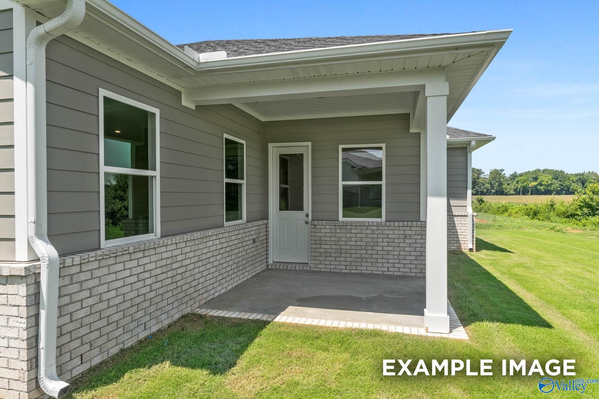 Modern 1-story Arcadia home exterior with gray siding, white brick base, covered porch, large windows, green lawn in Owens Cross Roads, AL