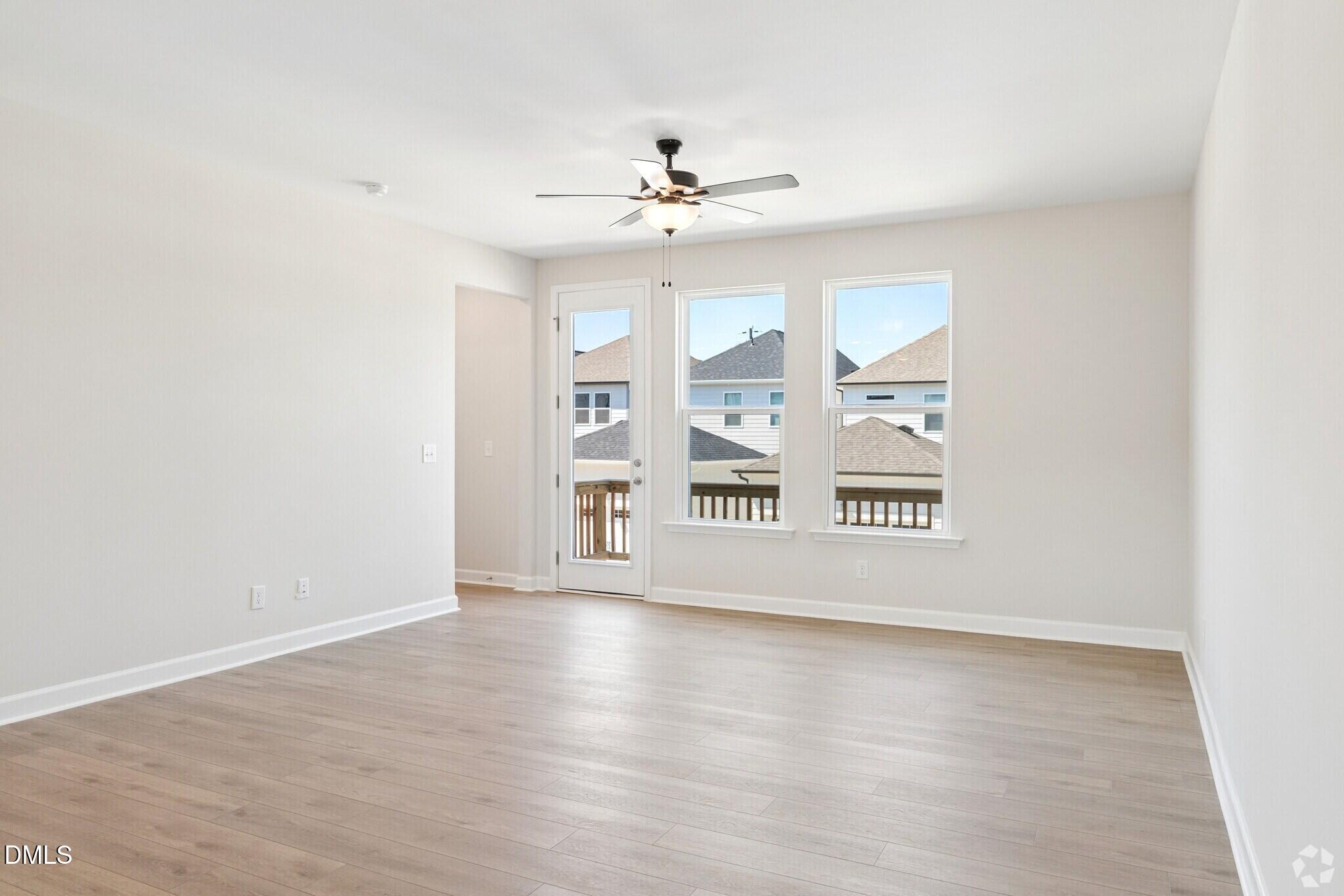Bright open living room with luxury vinyl plank floors, ceiling fan, and deck access in Davidson Homes townhome, Knightdale NC