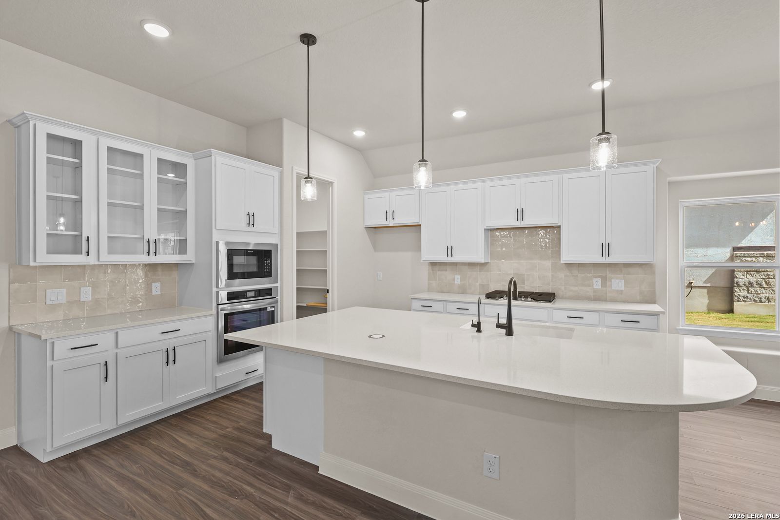 Modern white kitchen with large island and stainless appliances in The Summerlin B home by Davidson Homes, Potranco Oaks.