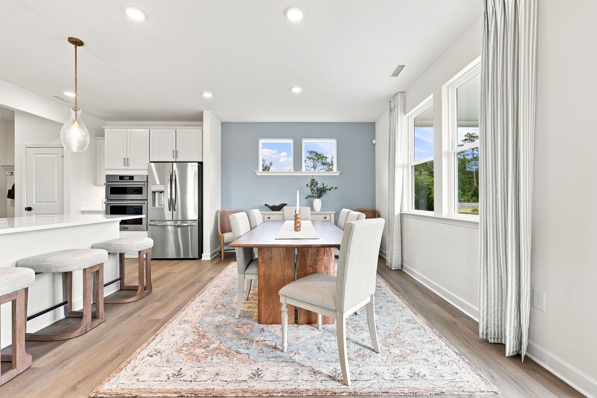 Open-concept dining room at Montrose in Aberdeen, NC by Davidson Homes with farmhouse table and modern kitchen island.