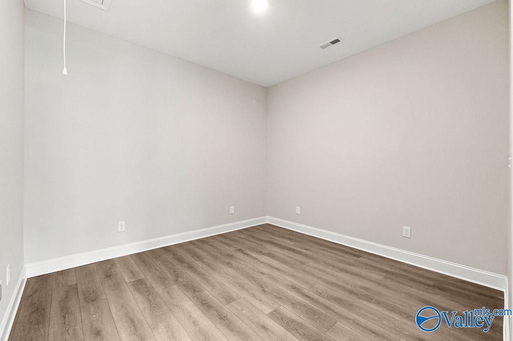 Bright, neutral bedroom with wood-style flooring in The Camilla C floor plan at The Retreat at Cain Park, Hartselle, AL.