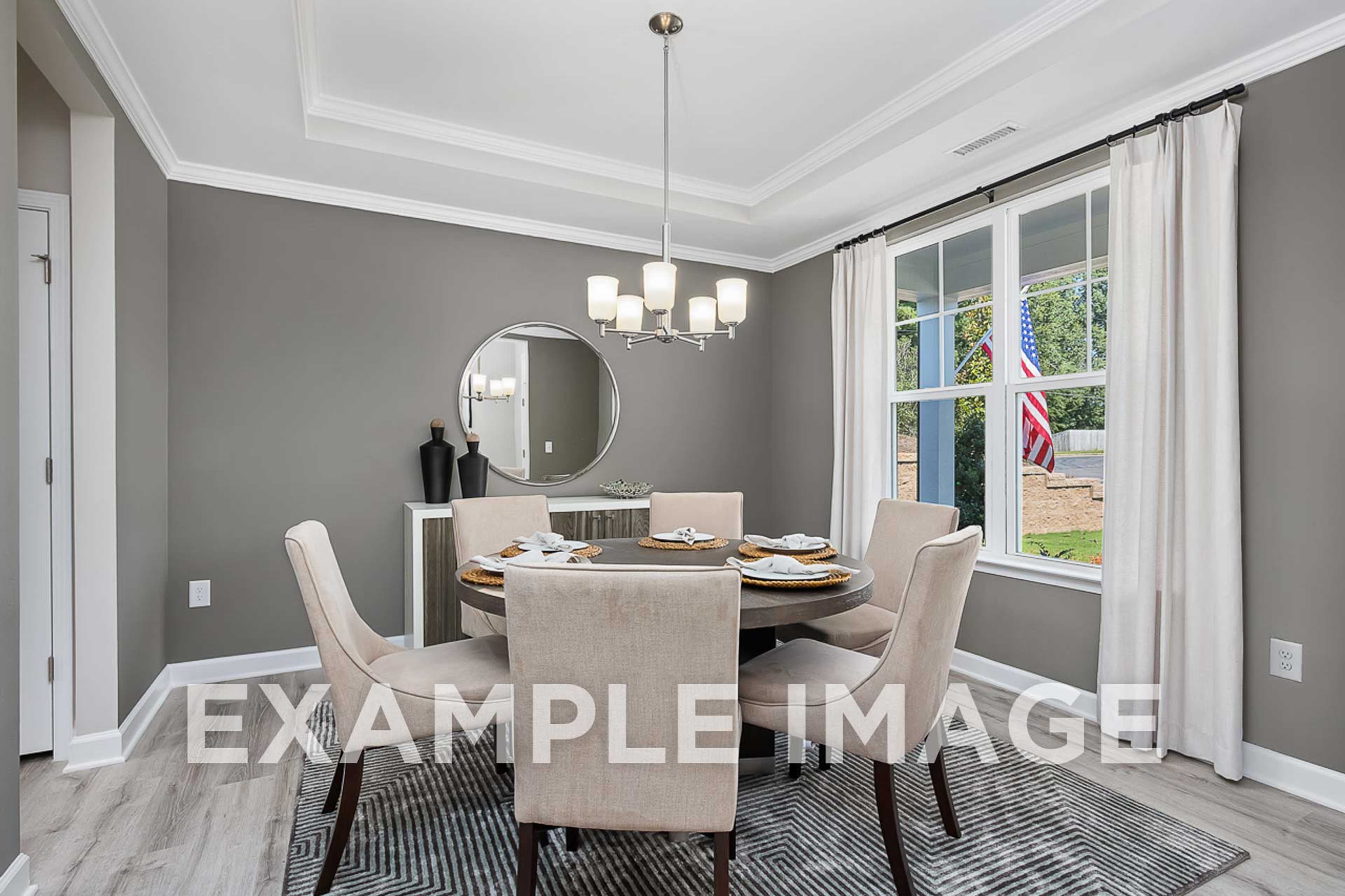 Spacious dining room in The Ash with round table, beige chairs, chandelier, gray walls, and large window