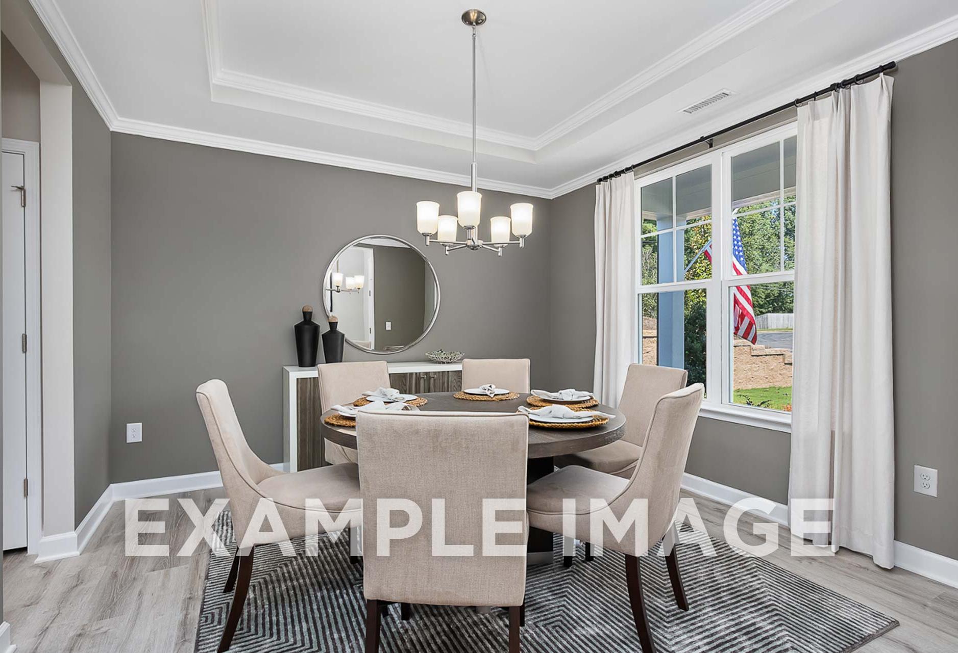 Spacious dining room in The Ash with round table, beige chairs, chandelier, gray walls, and large window