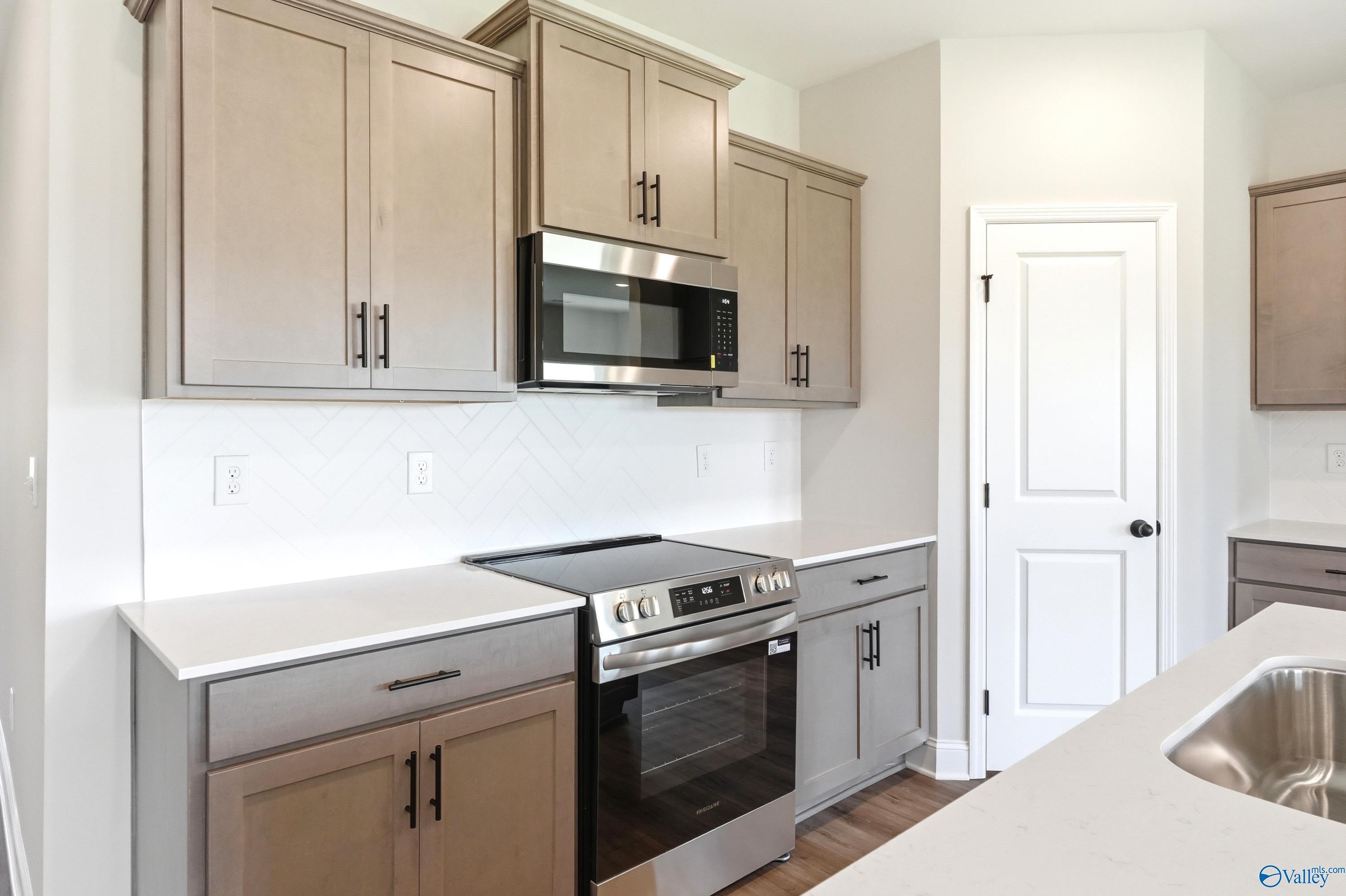 Modern kitchen with grey cabinets, white countertops, and stainless appliances in The Daphne floor plan, Hazel Green, AL.