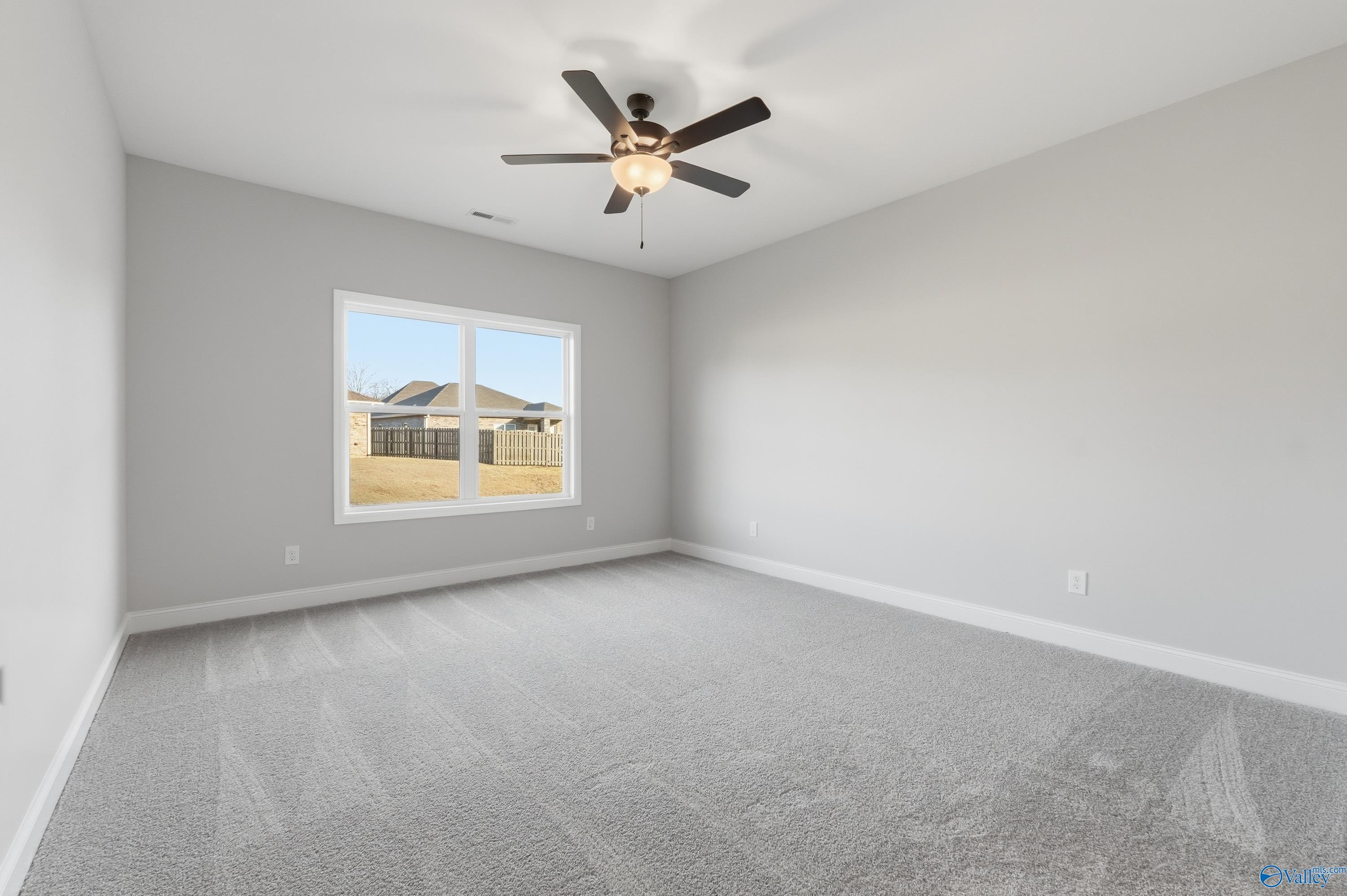 Bright secondary bedroom with ceiling fan, gray carpet, and window view of backyard in Davidson Homes The Daphne D, Arab, Alabama