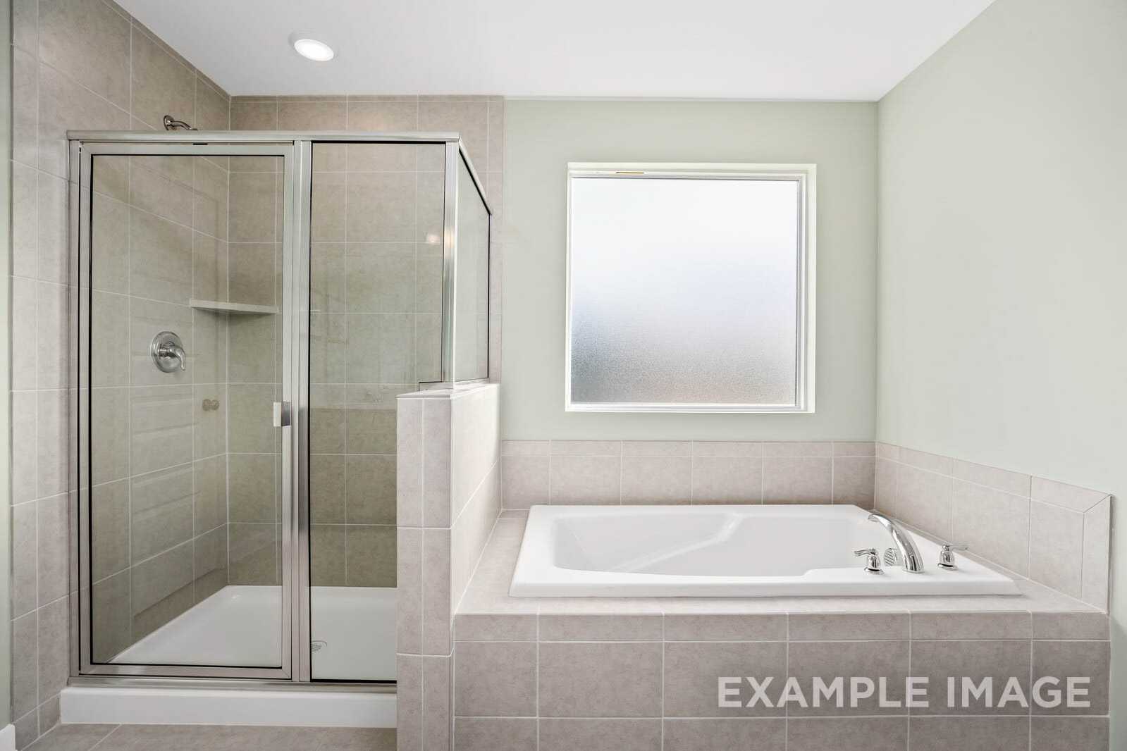 Spacious master bathroom in The Gordon B with glass-enclosed shower and soaking tub