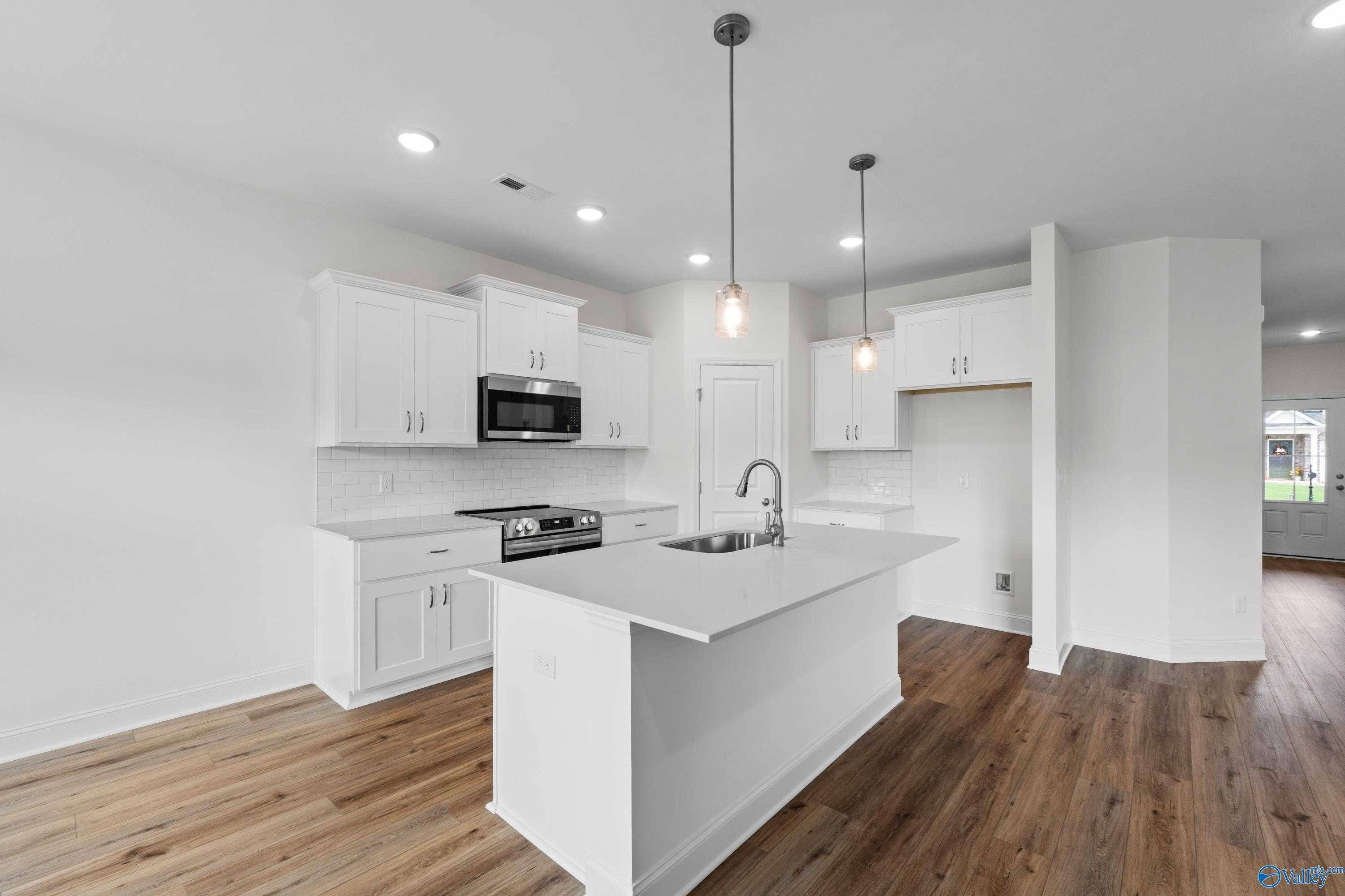 Bright open-concept kitchen with white shaker cabinets, stainless appliances, and center island in Davidson Homes The Asheville C, Athens Alabama